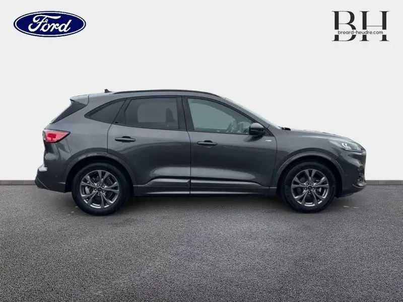 Vue de profil côté gauche d'un Ford Kuga 2023 gris Magnetic métallisé avec vitres arrière surteintées et jantes alu.