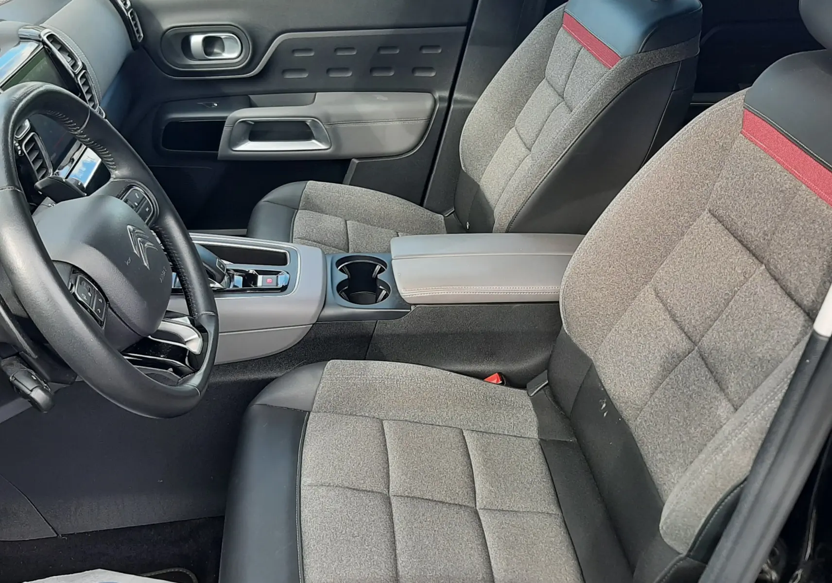 Vue intérieure côté conducteur du Citroën C5 Aircross 2020, sièges tissu gris avec bande rouge et volant cuir noir.