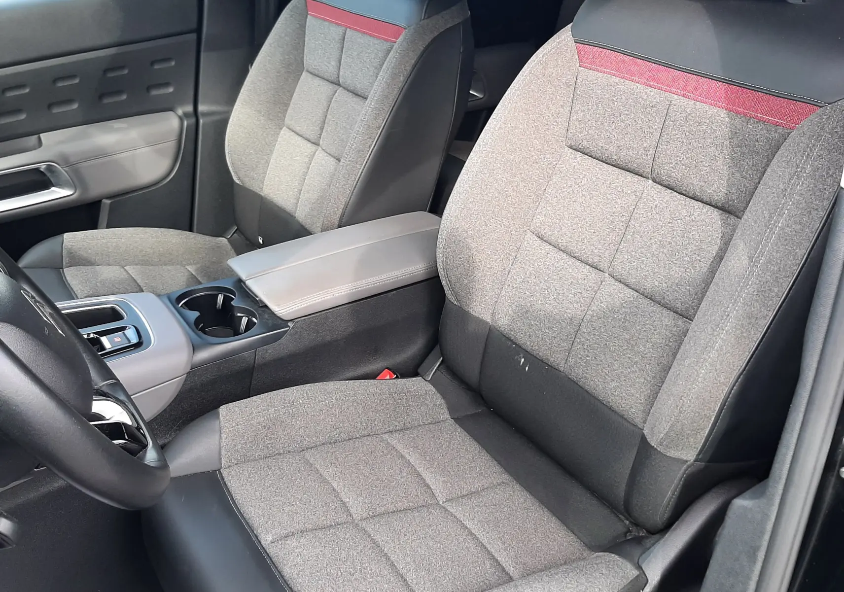 Vue intérieure côté gauche des sièges avant gris avec surpiqûres rouges et accoudoir central du Citroën C5 Aircross 2020.