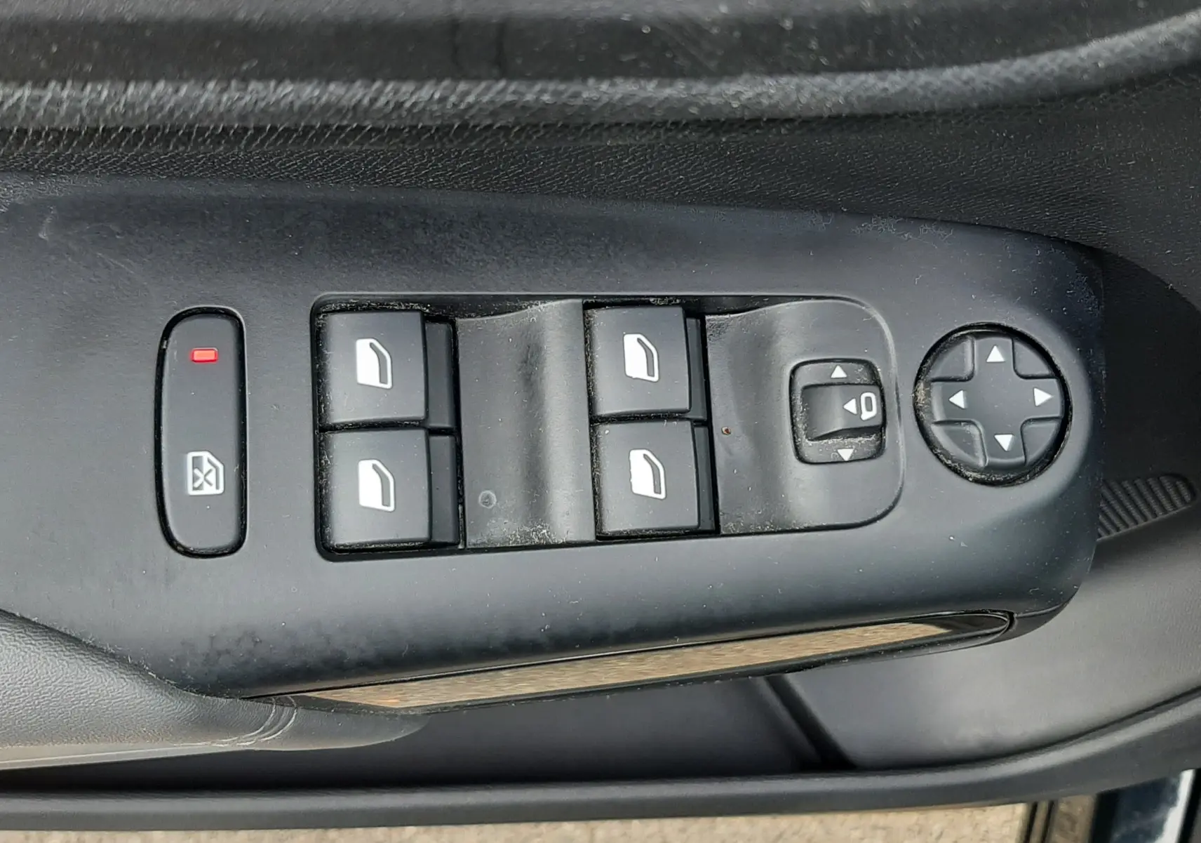 Gros plan sur la commande des vitres et rétroviseurs côté conducteur d’un Citroën C5 Aircross noir, avec boutons noirs et symbole blanc.