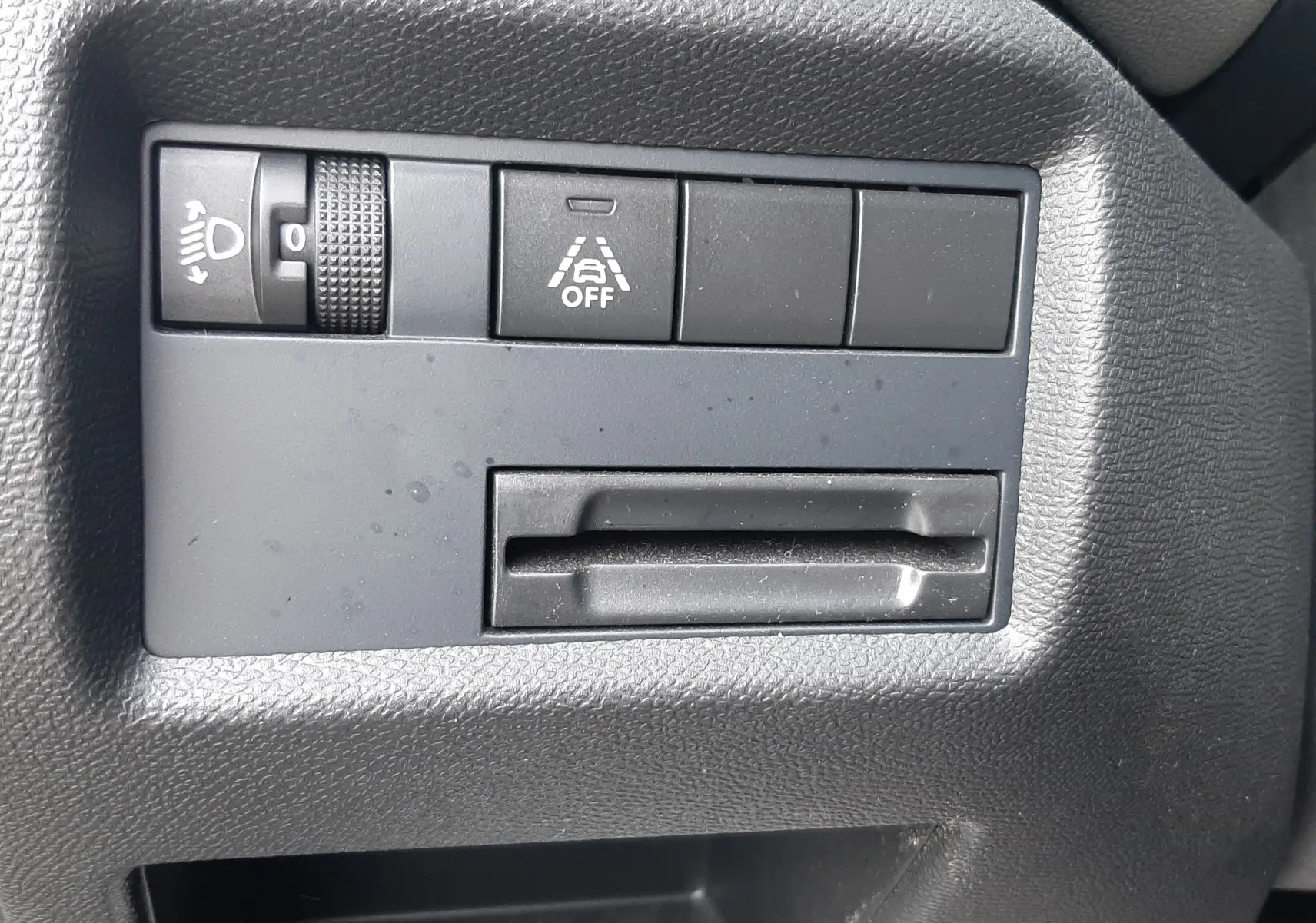 Détail intérieur montrant les commandes de réglage des phares et d'activation de l'alerte de franchissement de ligne sur Citroën C5 Aircross noir.