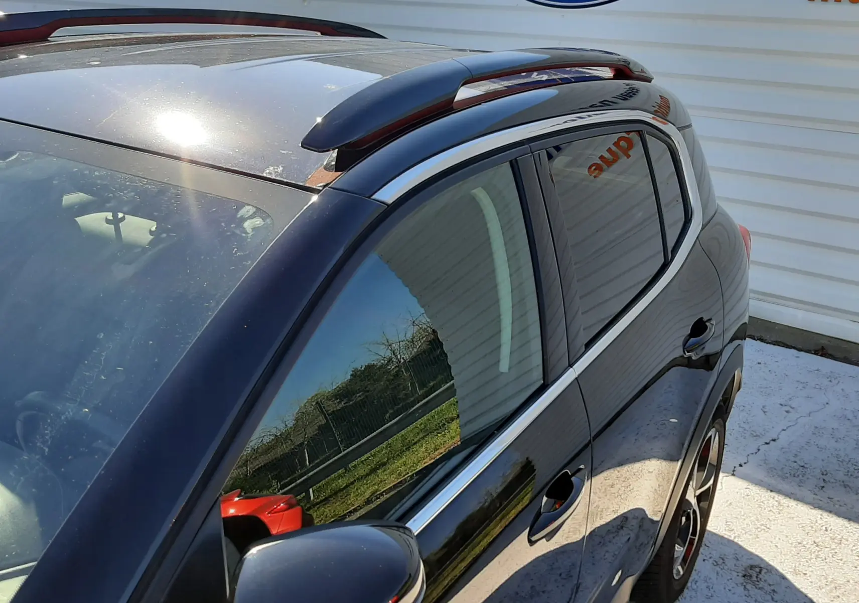 Vue de côté droit avant d'un Citroën C5 Aircross noir 2020 avec barres de toit et vitres teintées, reflet d'extérieur visible.