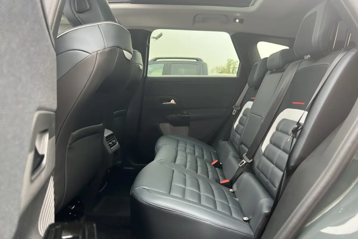 Vue latérale intérieure sur la banquette arrière cuir noir matelassé du Citroën C5 Aircross New Hybrid 2026 avec toit ouvrant panoramique.