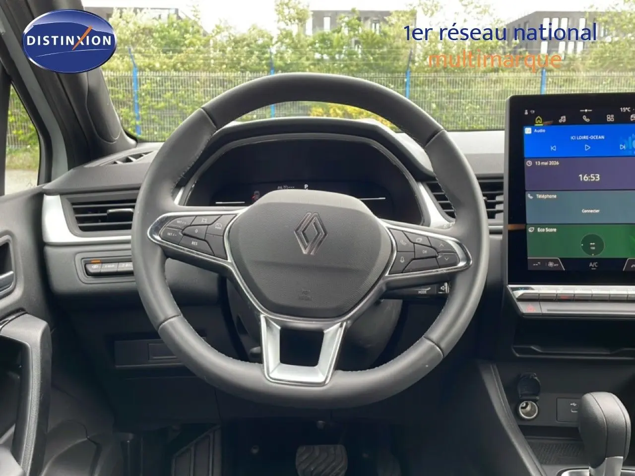 Vue intérieure centrée sur le volant cuir noir et l'écran tactile du tableau de bord de la Renault Symbioz hybride 2025.