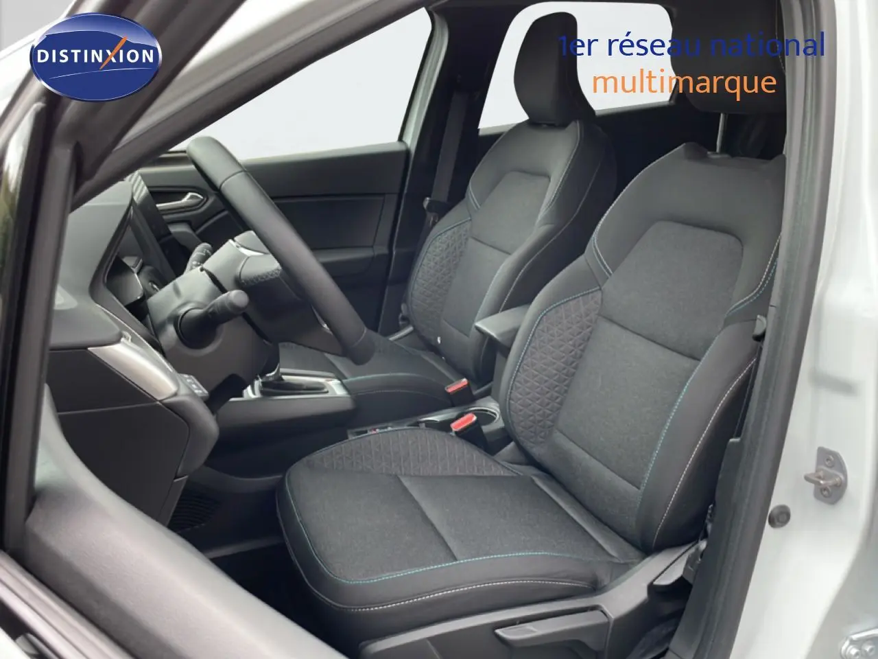 Vue intérieure côté gauche de la Renault SYMBIOZ blanche nacrée, mettant en valeur les sièges tissu noir avec surpiqûres bleues.