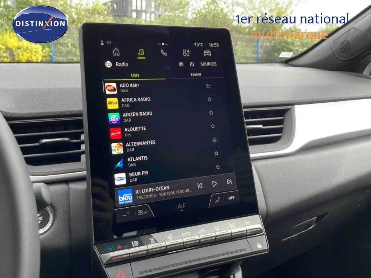 Vue intérieure du tableau de bord du Renault Symbioz blanc nacré, avec écran tactile central affichant les stations radio.