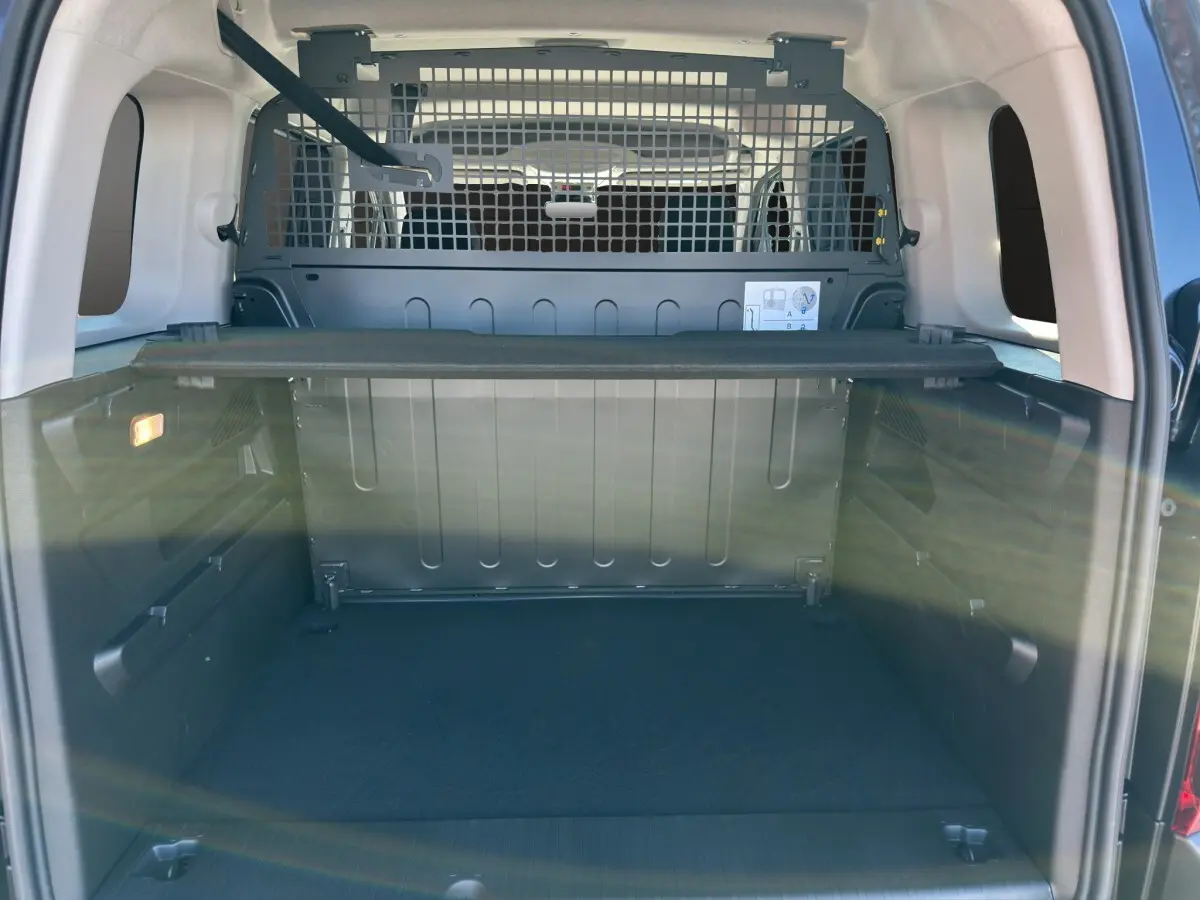 Vue intérieure du coffre noir du Citroën Berlingo 2026 avec séparation métallique et tablette de rangement.