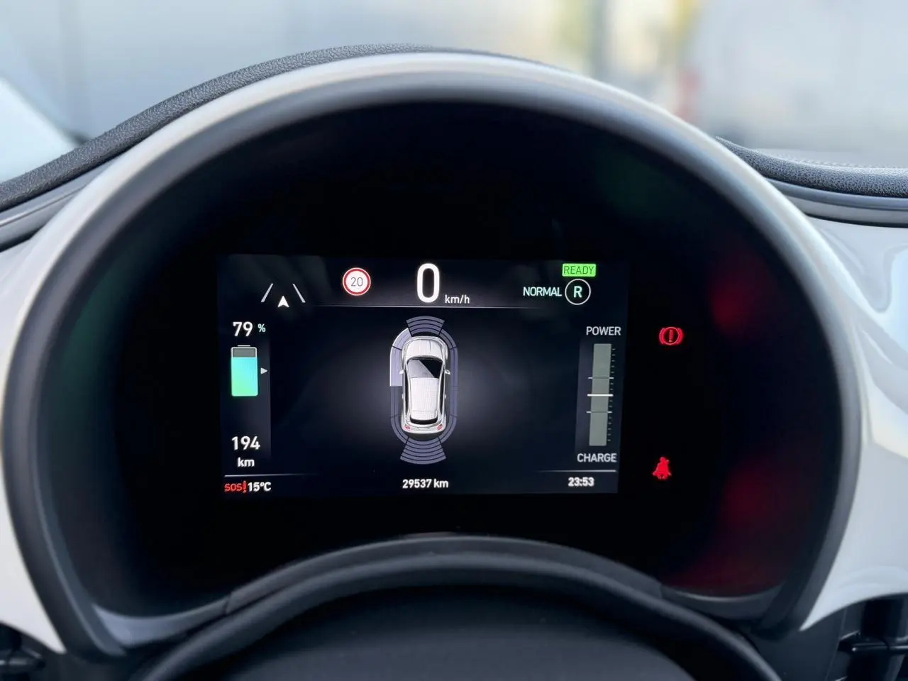 Gros plan sur l'instrumentation numérique de la Fiat 500 électrique blanche, affichant l'autonomie et les alertes.