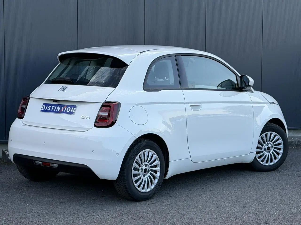 Vue 3/4 arrière droite d'une Fiat 500 électrique blanche Arctic avec jantes multibranches et feux arrière foncés.