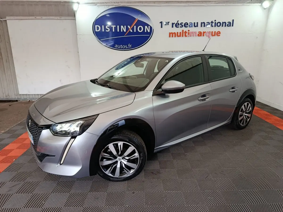 Peugeot 208 électrique gris clair vue 3/4 avant droit, avec phares LED et jantes distinctives en concession.