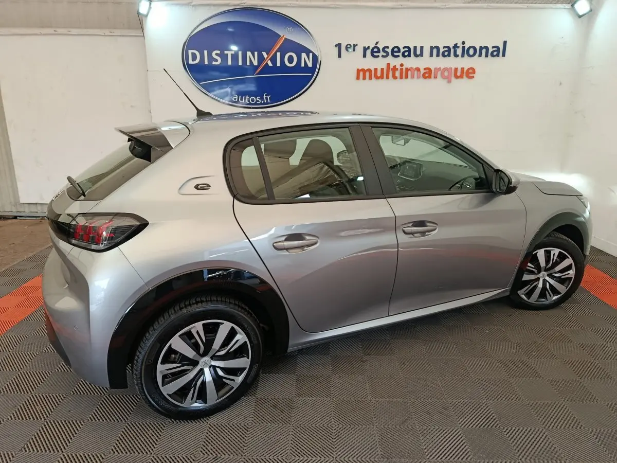 Profil droit d'une Peugeot 208 électrique Active Business gris clair avec jantes distinctives et logo "e" sur l'aile arrière.