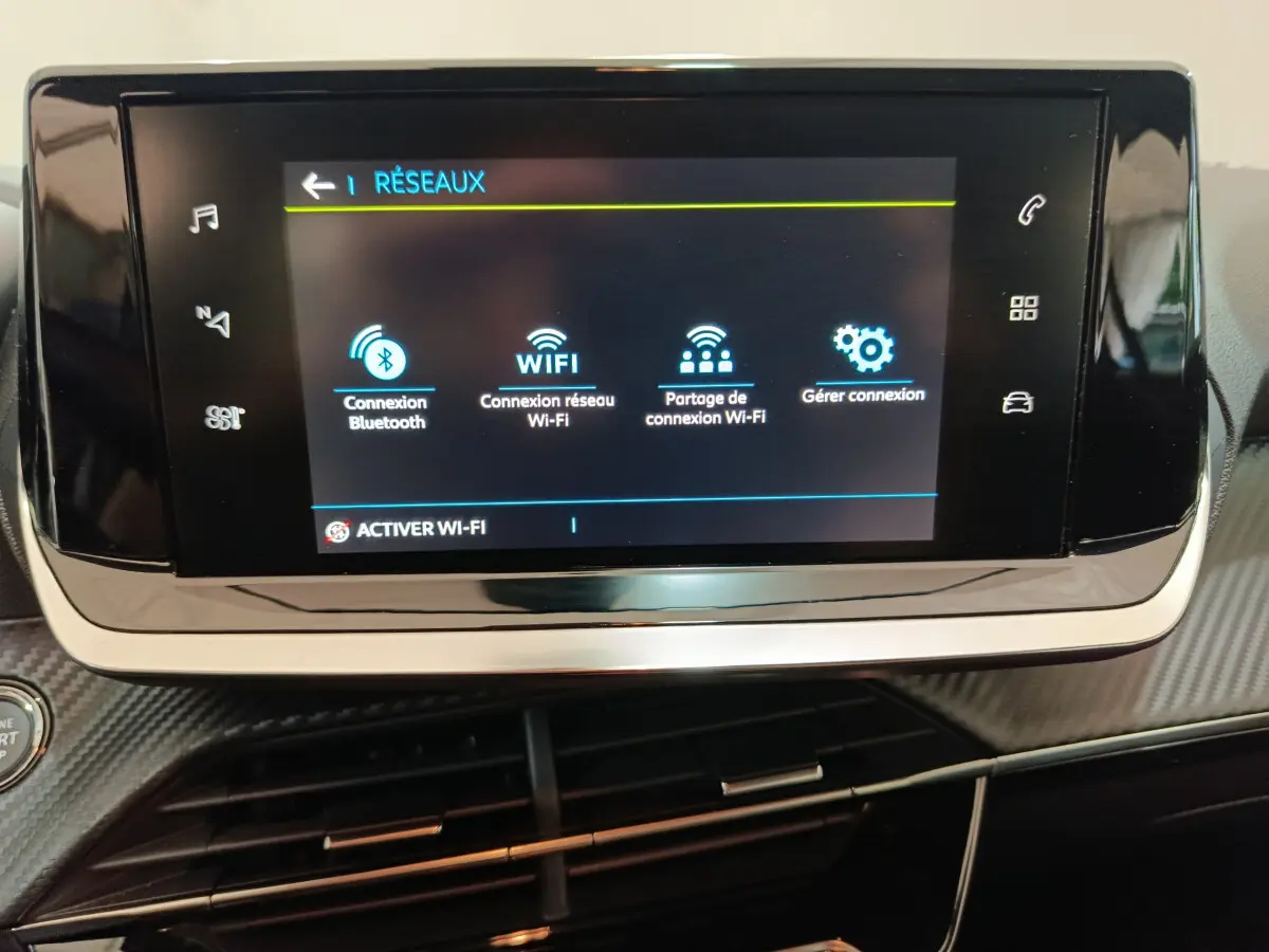 Écran tactile central affichant les options réseau dans l’habitacle d’une Peugeot 208 électrique gris clair.