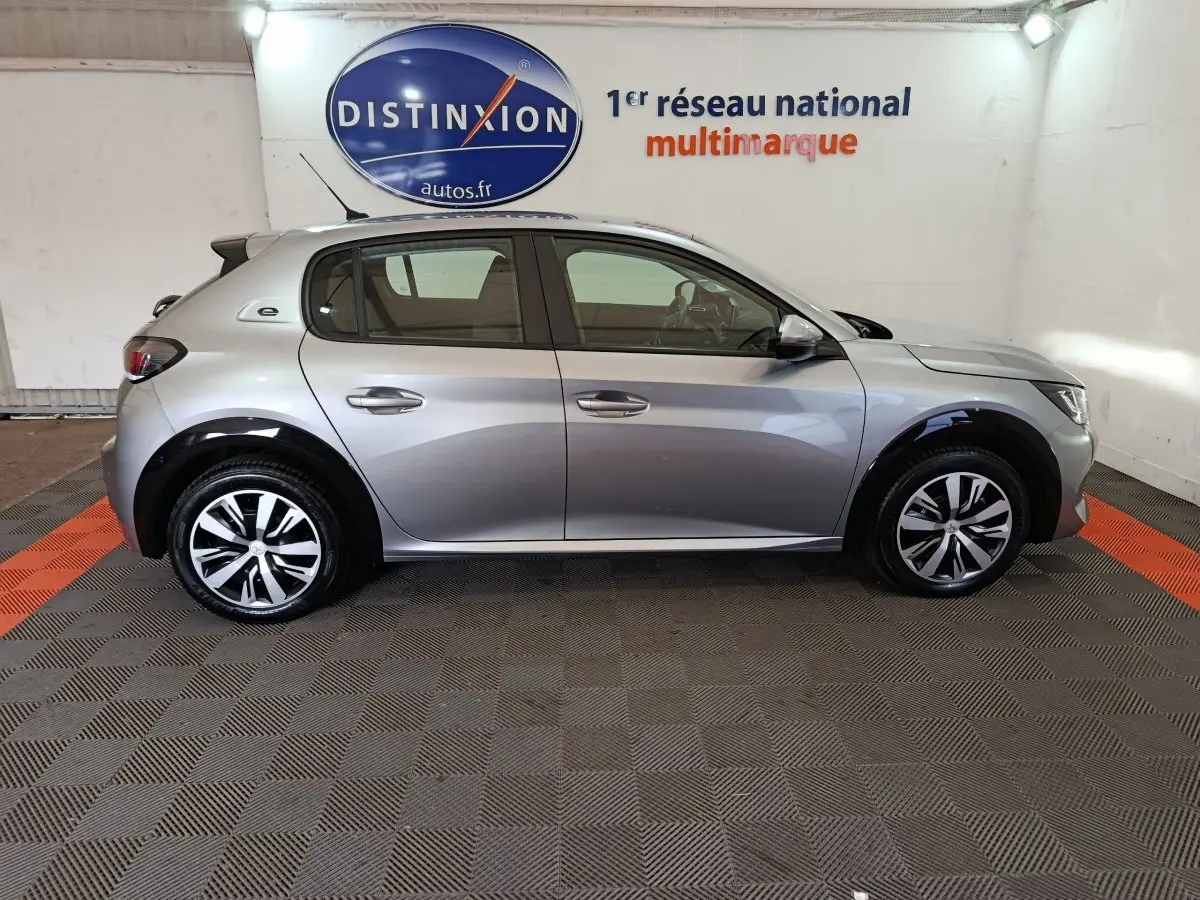 Profil côté gauche d'une Peugeot 208 électrique Active Business gris clair, avec jantes modernes et détails noirs contrastants.