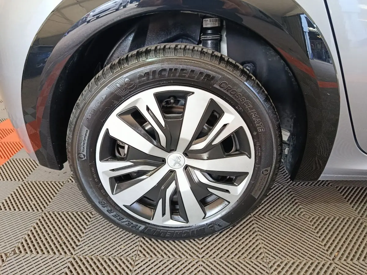 Gros plan sur la roue avant gauche gris clair d'une Peugeot 208 Electrique Active Business, jante moderne à motifs noirs et argentés.