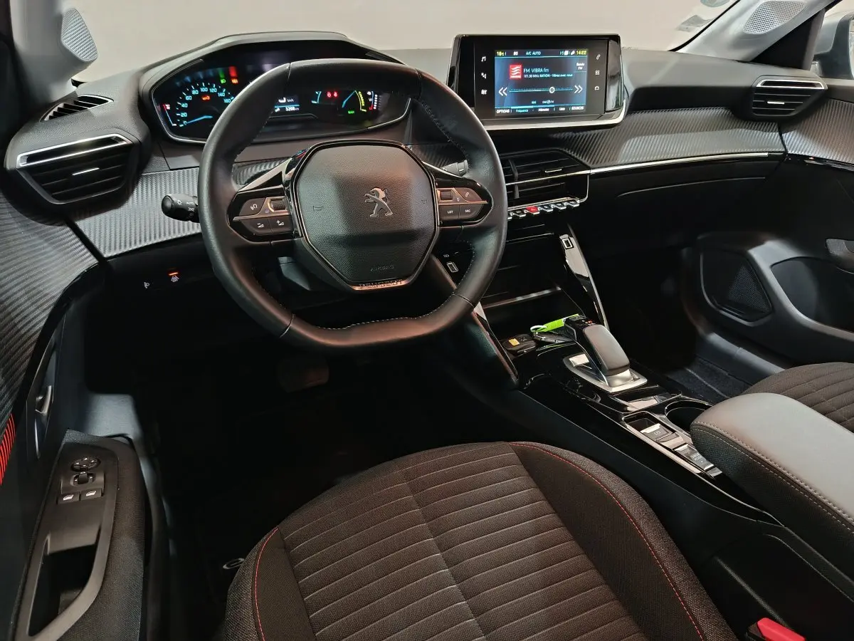 Intérieur de la Peugeot 208 électrique 2020, vue du poste de conduite avec volant cuir et écran tactile central.
