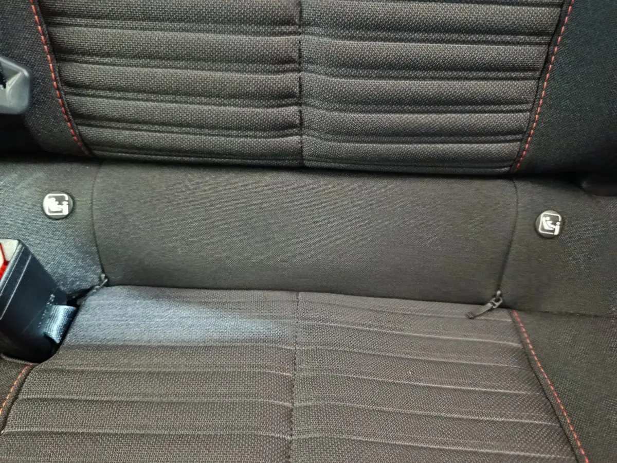 Gros plan sur la banquette arrière noire avec surpiqûres rouges et fixations Isofix du Peugeot 208 Electrique Active Business.
