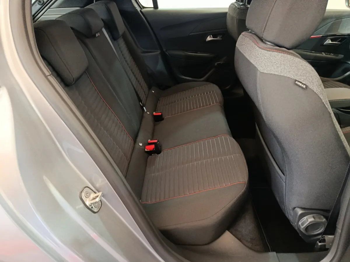 Vue intérieure côté droit sur la banquette arrière noire avec surpiqûres rouges d'une Peugeot 208 Electrique Active Business gris clair 2020.