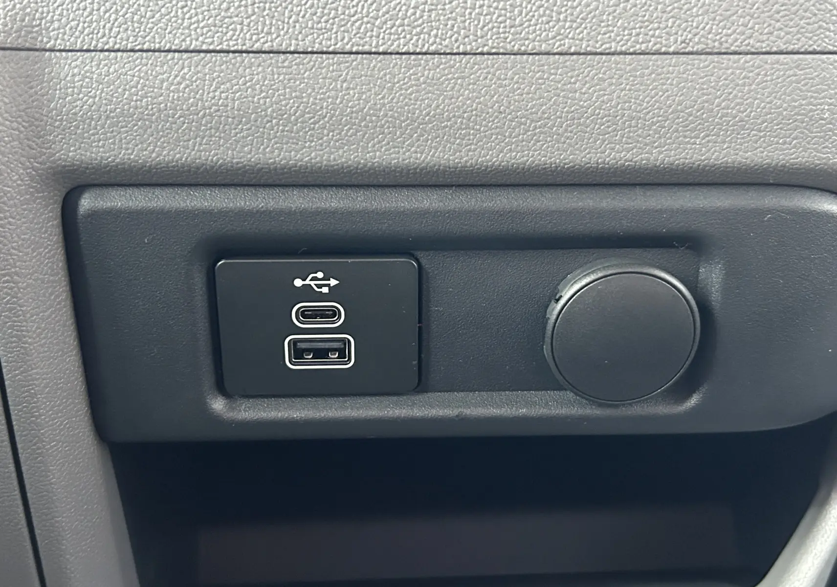 Gros plan sur les ports USB et prise 12V intégrés dans la console intérieure du Volkswagen Transporter T7 ProCab graphite.