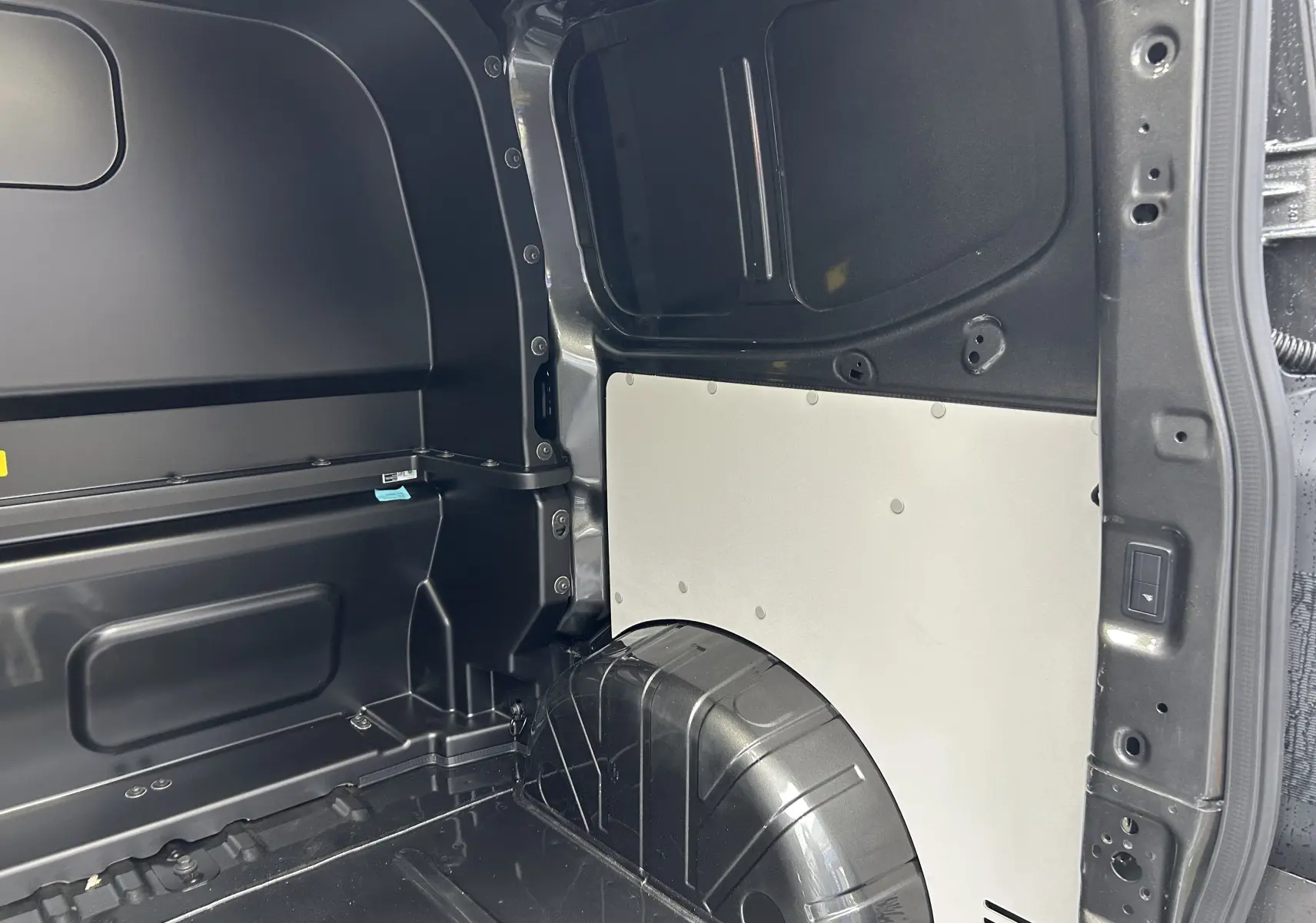 Vue intérieure arrière droite du Volkswagen Transporter T7 ProCab L1H1 Business en graphite dust, montrant la zone de chargement vide.