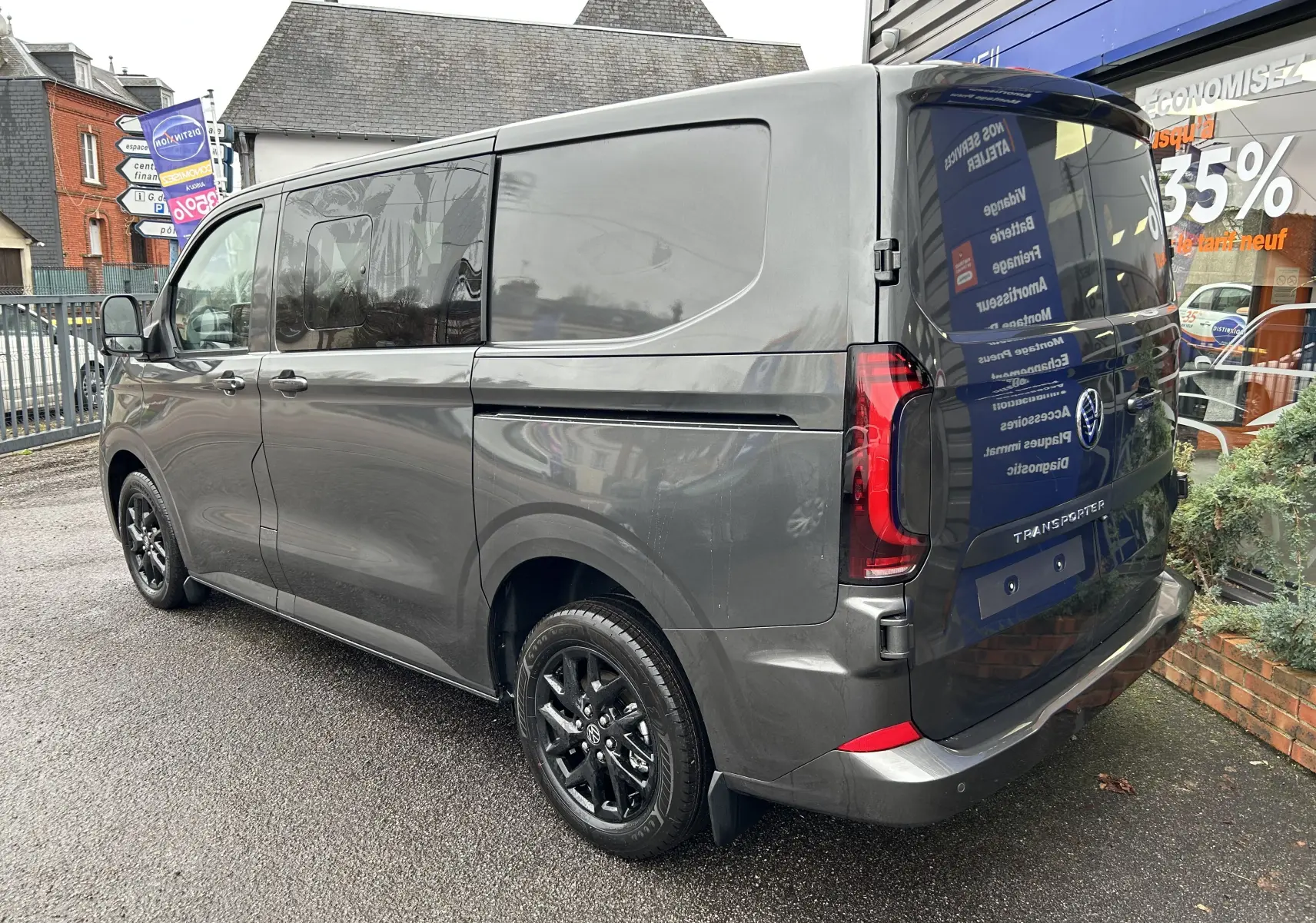 Vue 3/4 arrière droite du Volkswagen Transporter T7 ProCab graphite avec jantes noires brillantes et vitres teintées.