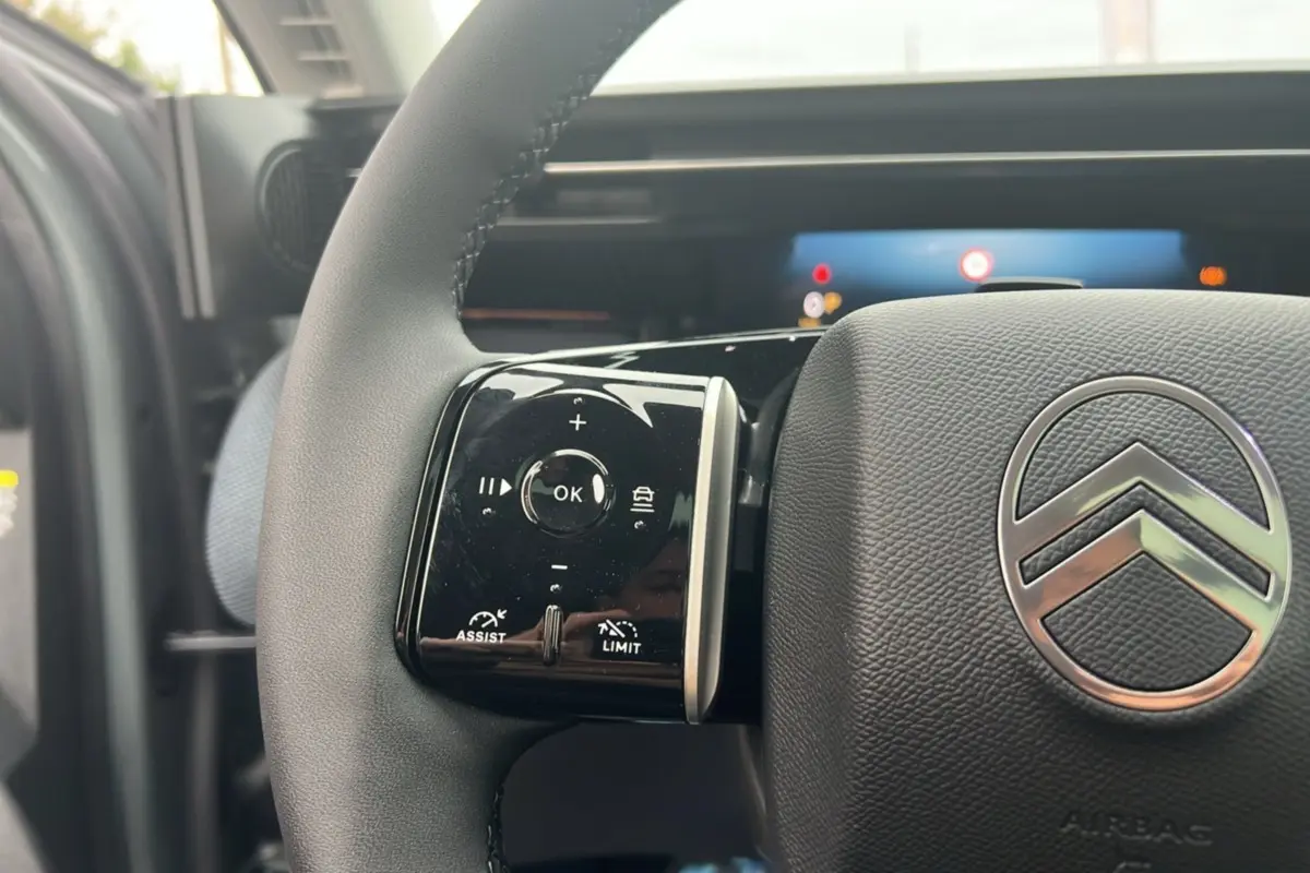 Gros plan sur le volant cuir multifonctions Citroën C5 Aircross New Hybrid, avec commandes intégrées et logo chromé central.