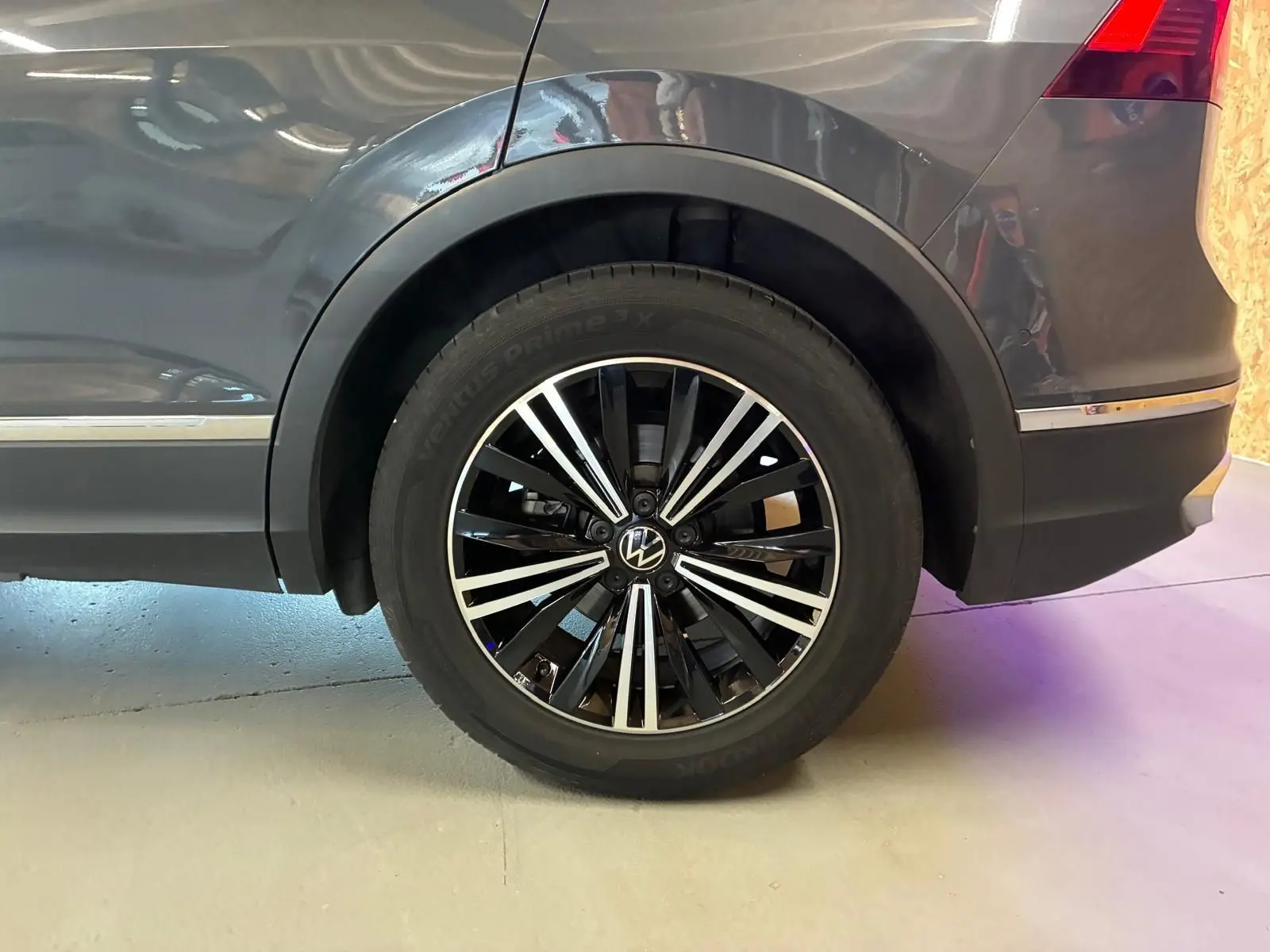 Gros plan sur la roue arrière droite du Volkswagen Tiguan gris 2023, avec jante alliage noire et argentée.