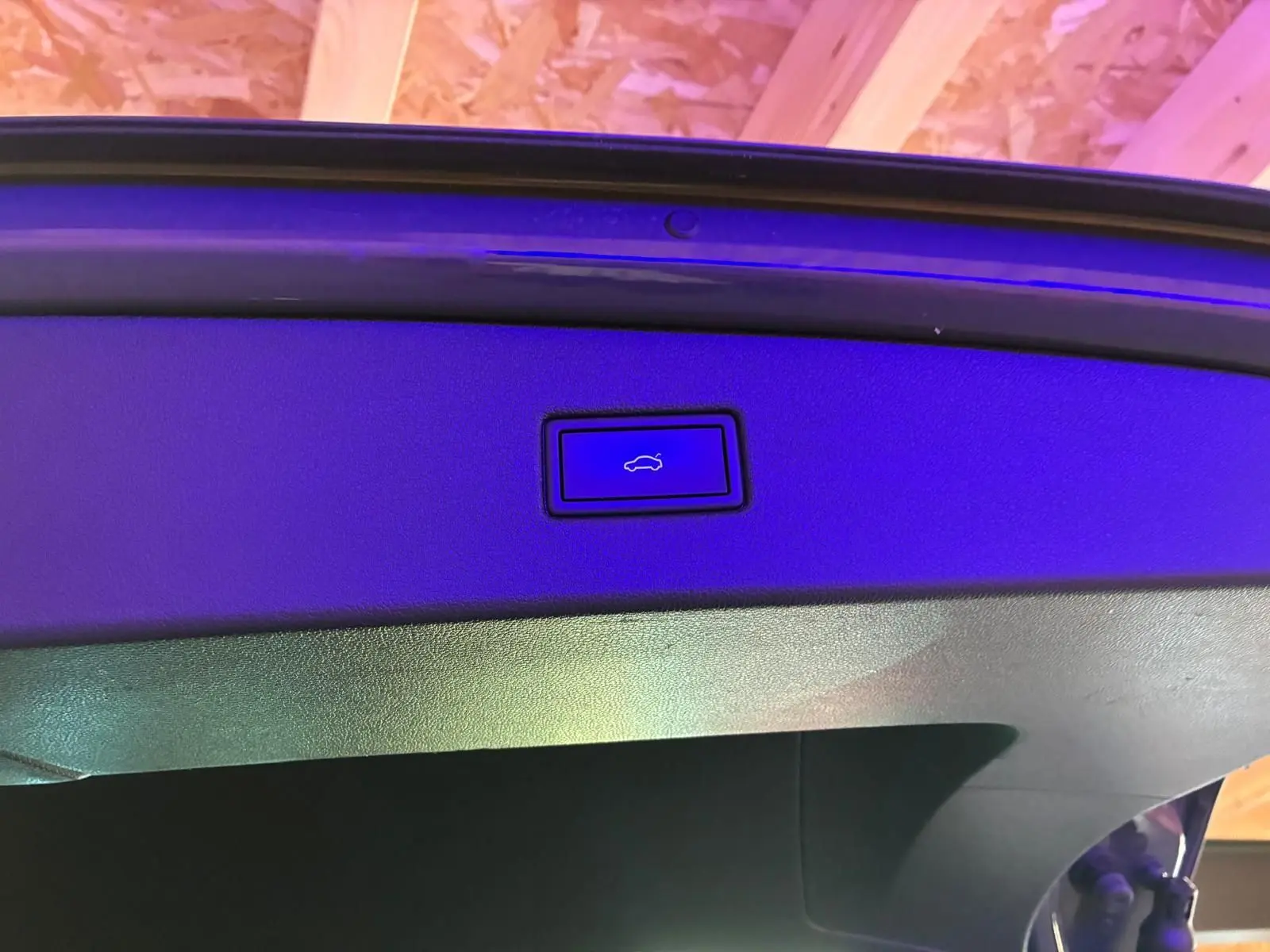 Gros plan sur le bouton d'ouverture électrique du hayon du Volkswagen Tiguan gris, intérieur du coffre visible.