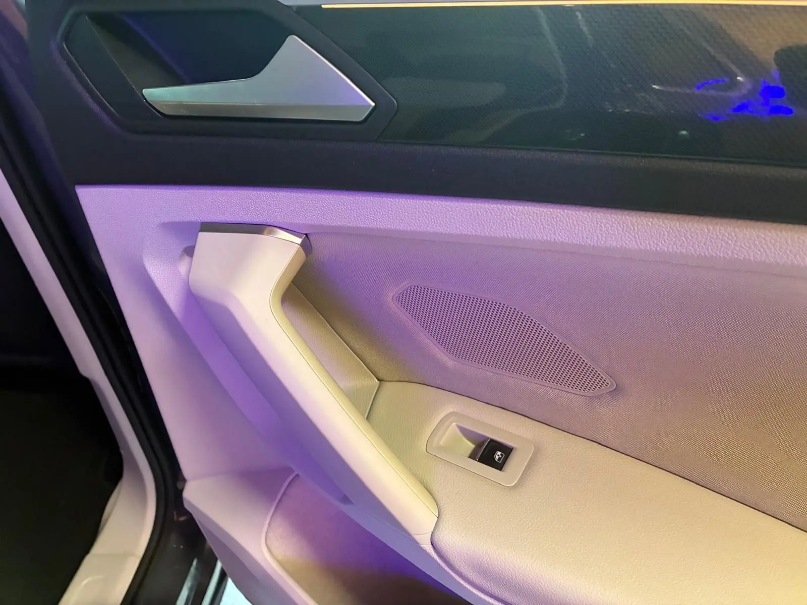 Gros plan sur la poignée de porte intérieure beige et noire du Volkswagen Tiguan 2023, côté gauche.