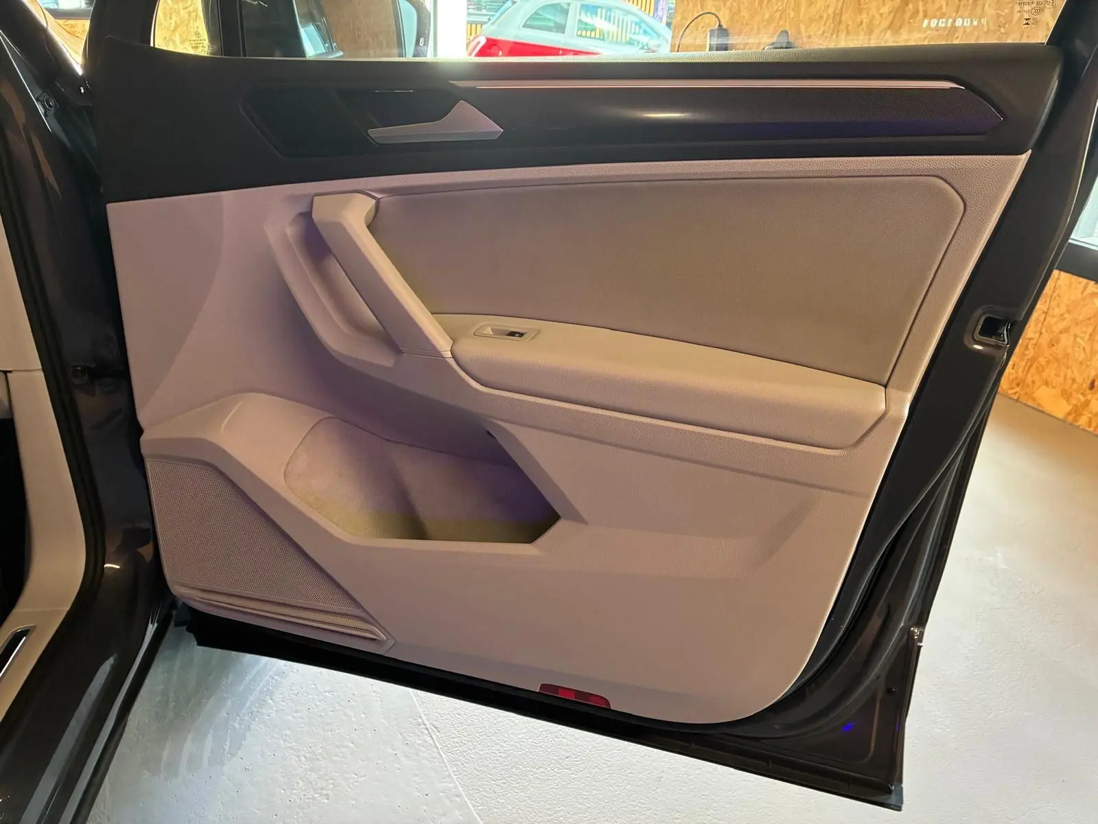 Vue intérieure de la porte avant droite du Volkswagen Tiguan 2023 gris, avec garniture beige et poignée intégrée.