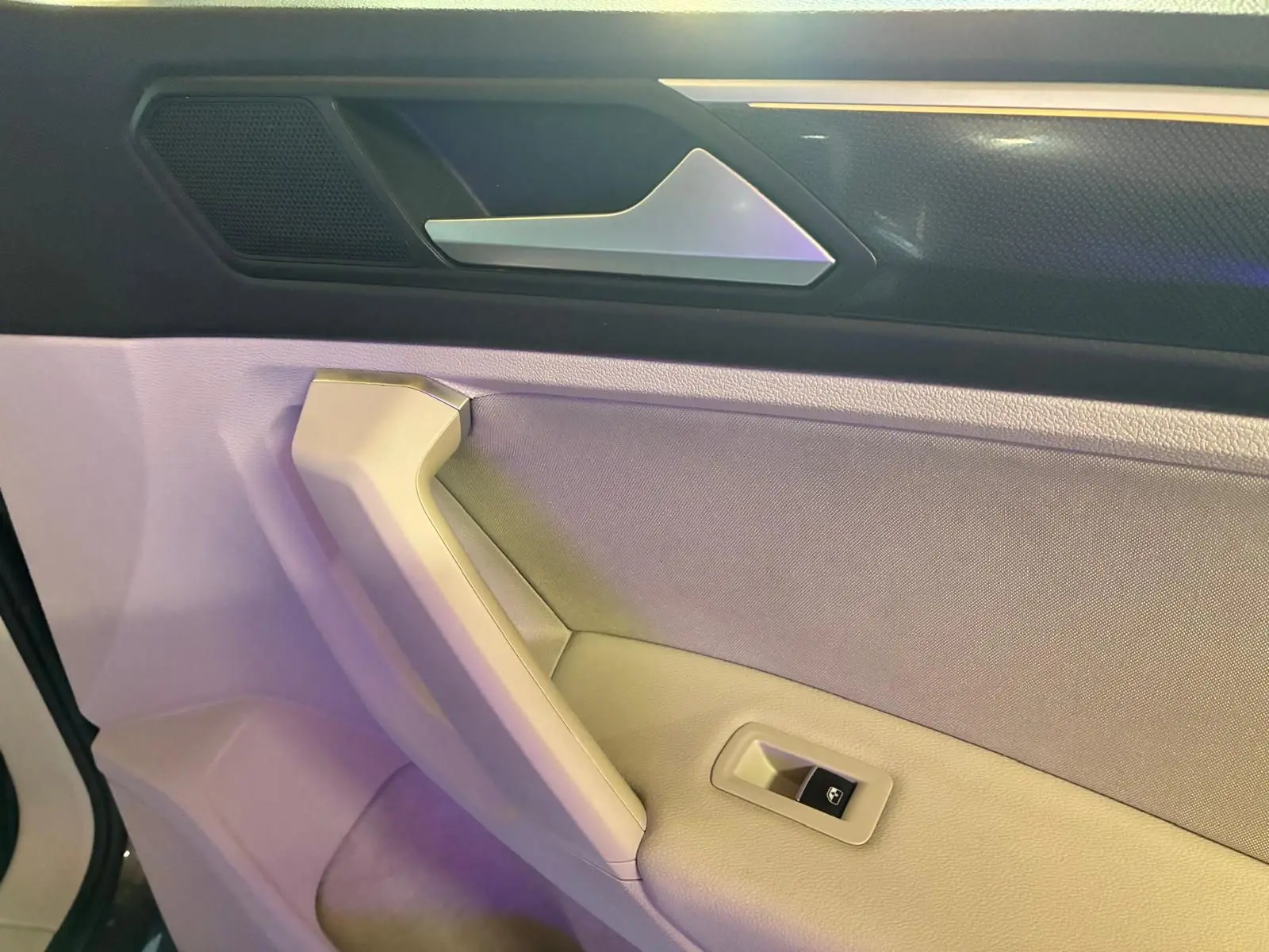 Détail de la poignée intérieure et commande de vitre côté conducteur du Volkswagen Tiguan 2023 gris.