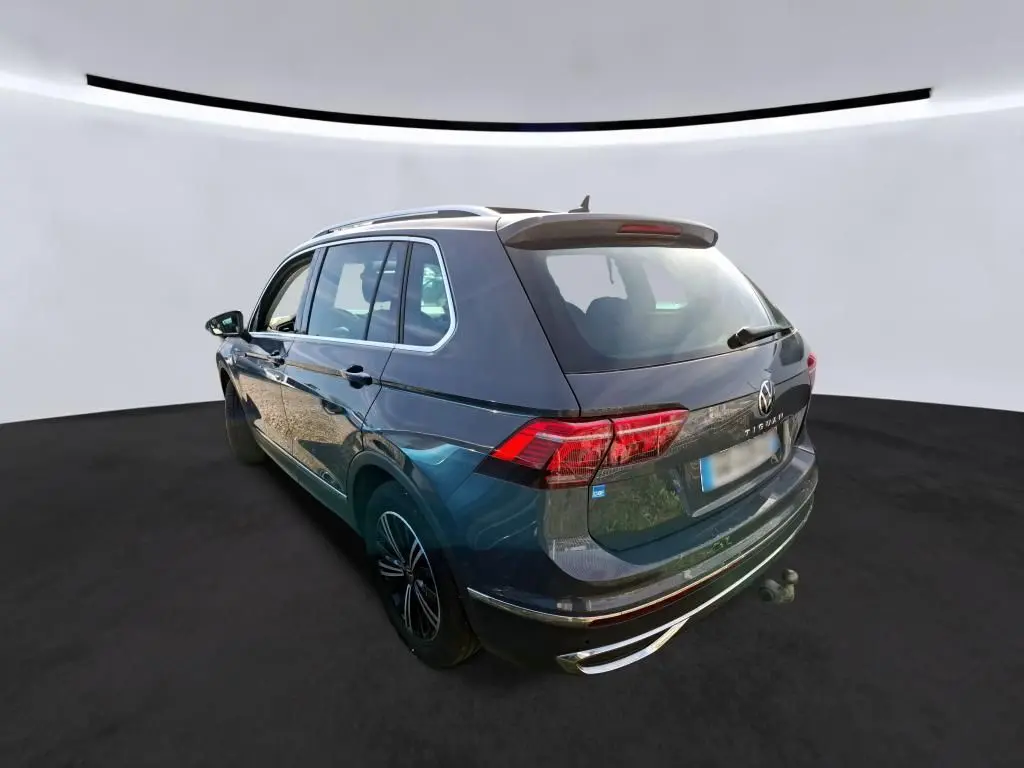 Volkswagen Tiguan gris 3/4 avant droit en showroom avec calandre chromée et jantes noires.