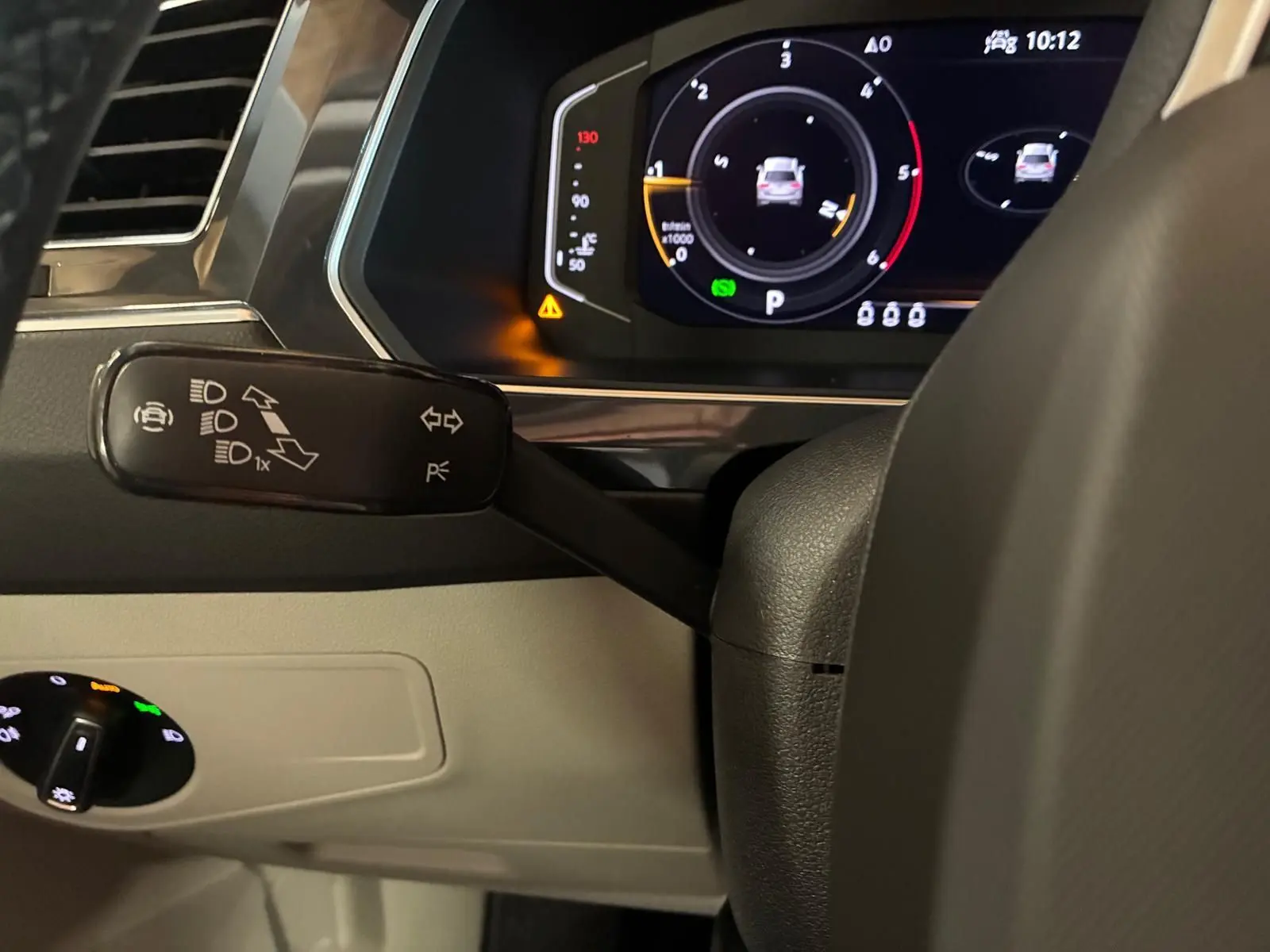 Gros plan sur le combiné d'instruments digital et la commande de clignotants du Volkswagen Tiguan 2023, intérieur noir et beige.
