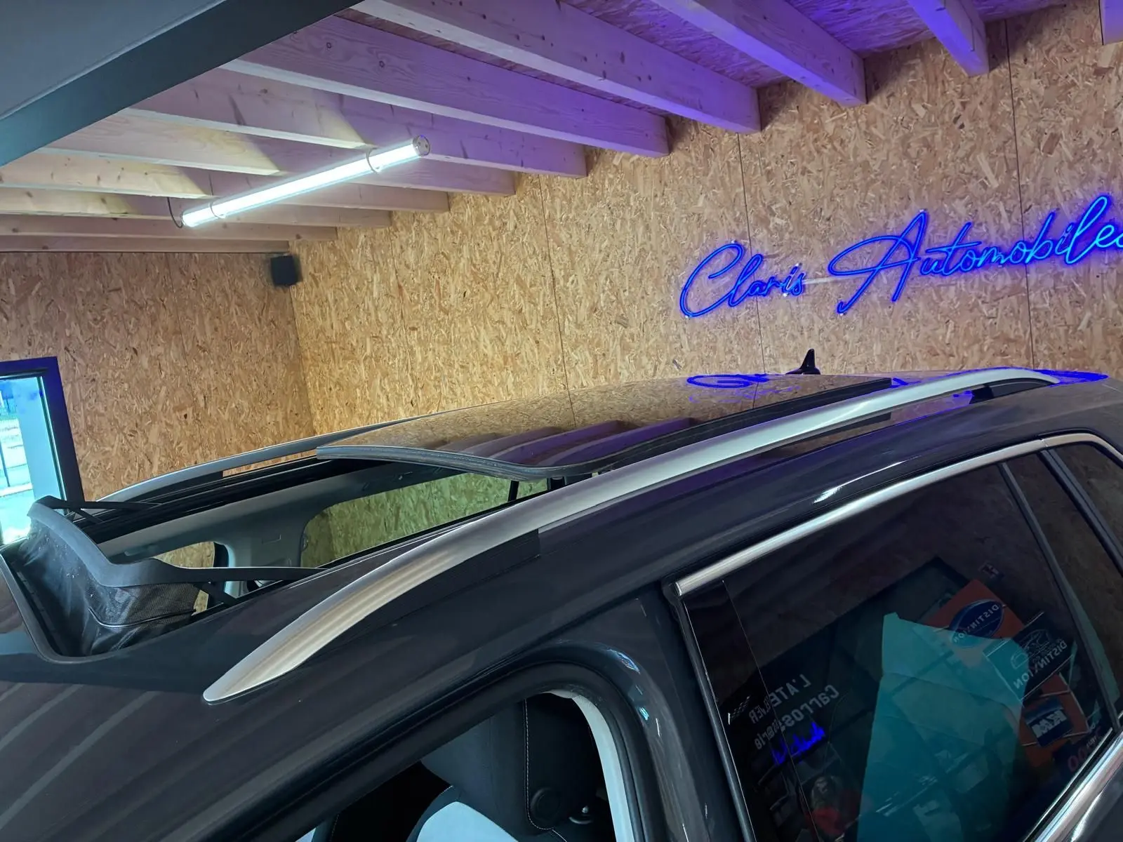 Vue rapprochée du toit ouvrant panoramique ouvert sur un Volkswagen Tiguan gris, angle côté gauche arrière.