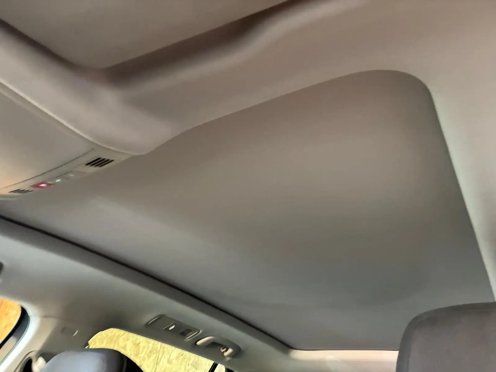 Vue intérieure du toit ouvrant panoramique fermé du Volkswagen Tiguan gris 2023, avec commandes intégrées au plafond.