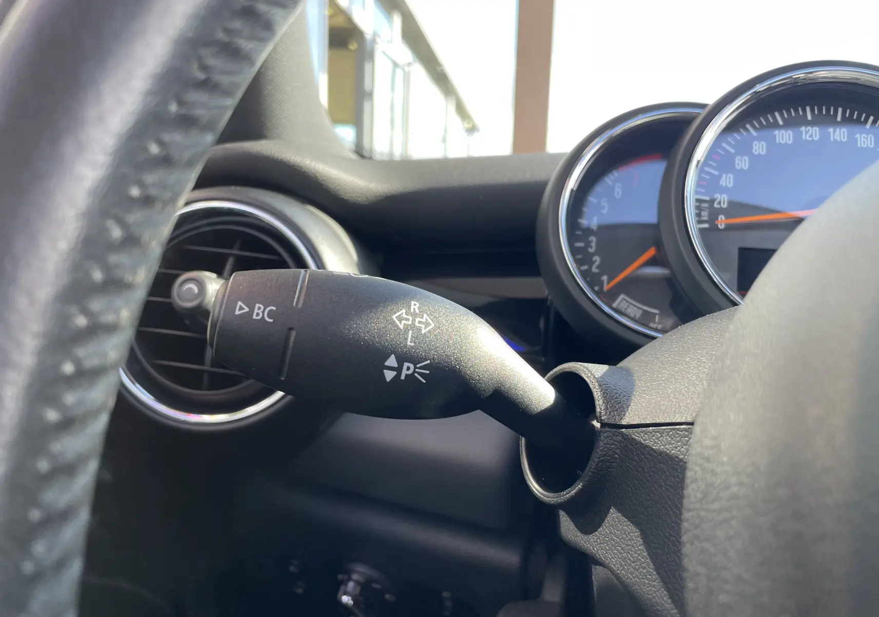 Gros plan sur la manette de clignotant à gauche du volant dans l'habitacle gris noir d'une MINI F56 Cooper S 2015.