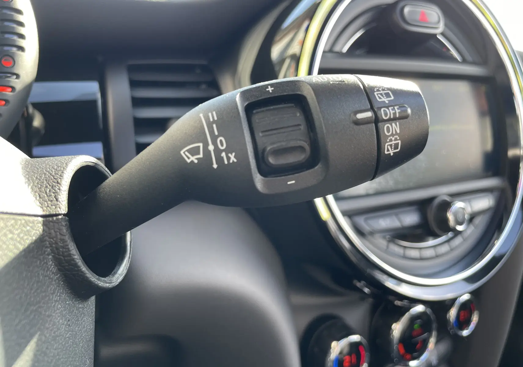 Gros plan sur la commande d'essuie-glace dans l'habitacle gris noir d'une MINI F56 Cooper S 2015 avec tableau de bord rond.