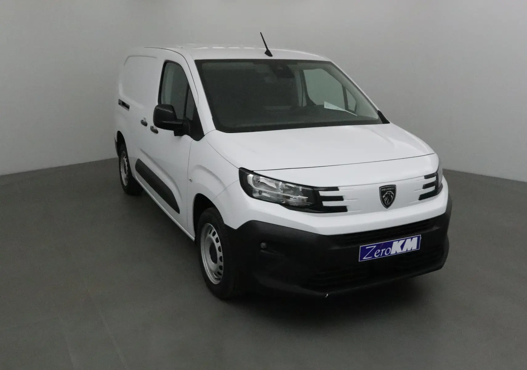 Peugeot Partner blanc en 3/4 avant droit, avec calandre noire et logo lion sur fond blanc.