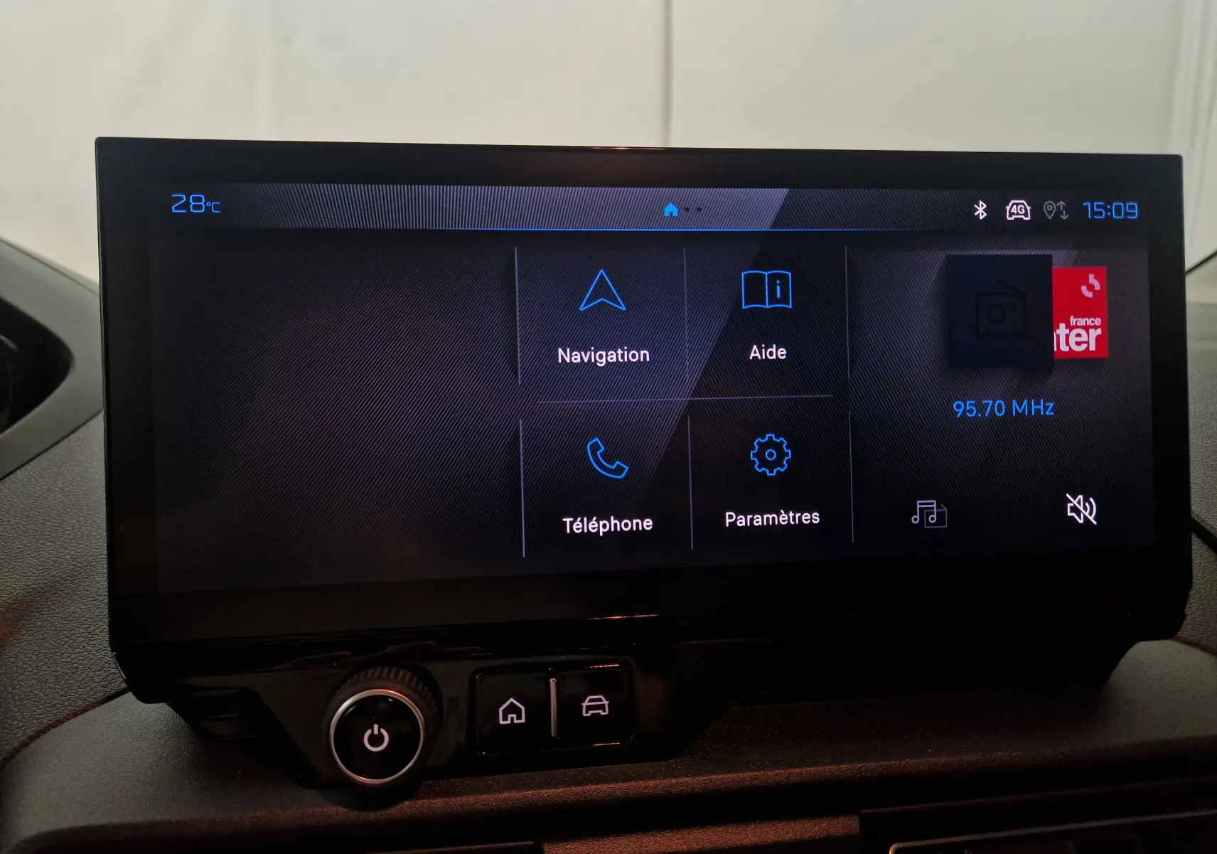 Écran tactile central du Peugeot Partner 2025 affichant les options Navigation, Aide, Téléphone et Paramètres, ambiance intérieure noire.