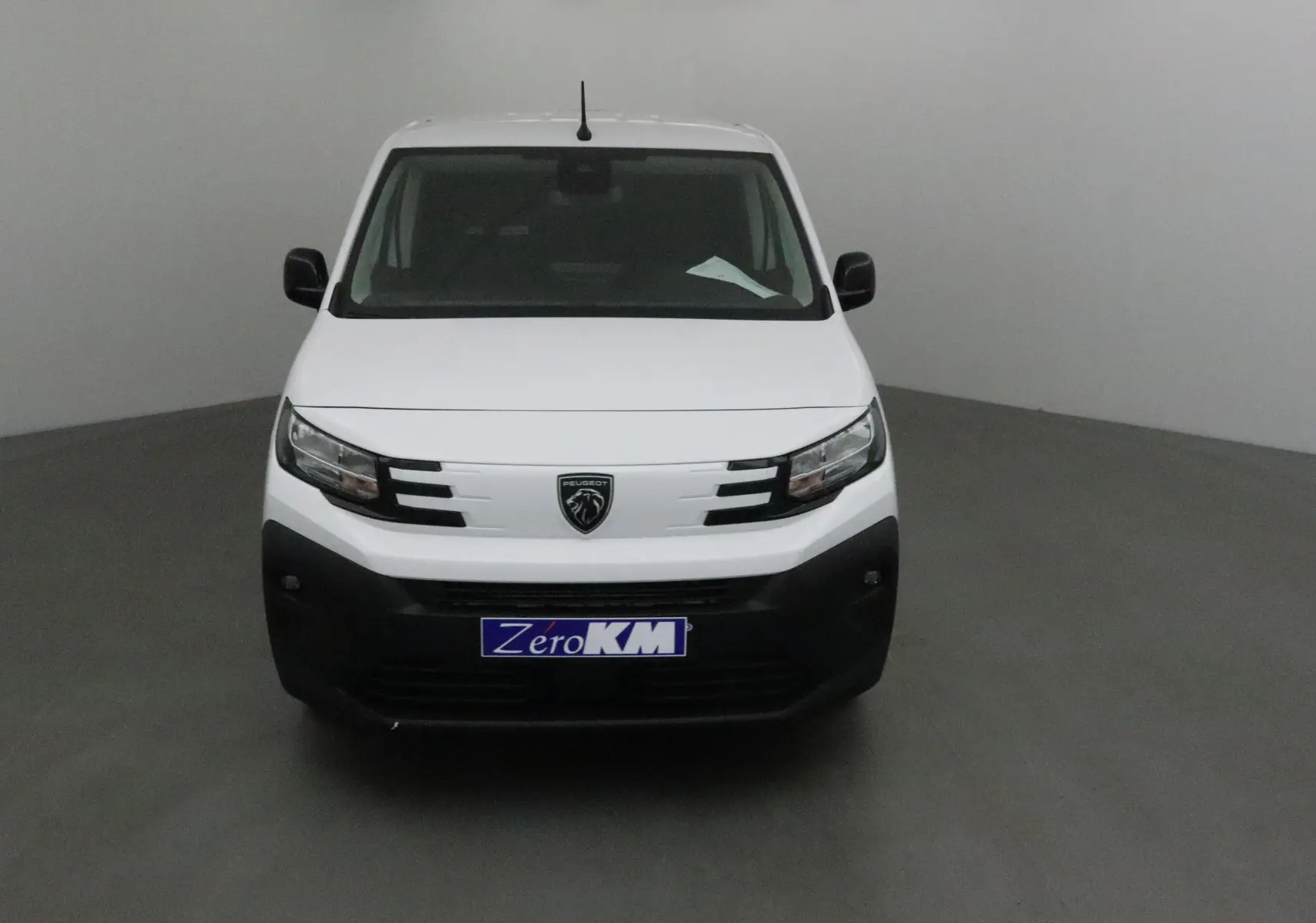 Vue frontale d'un Peugeot Partner blanc avec pare-chocs noir et logo lion au centre de la calandre.