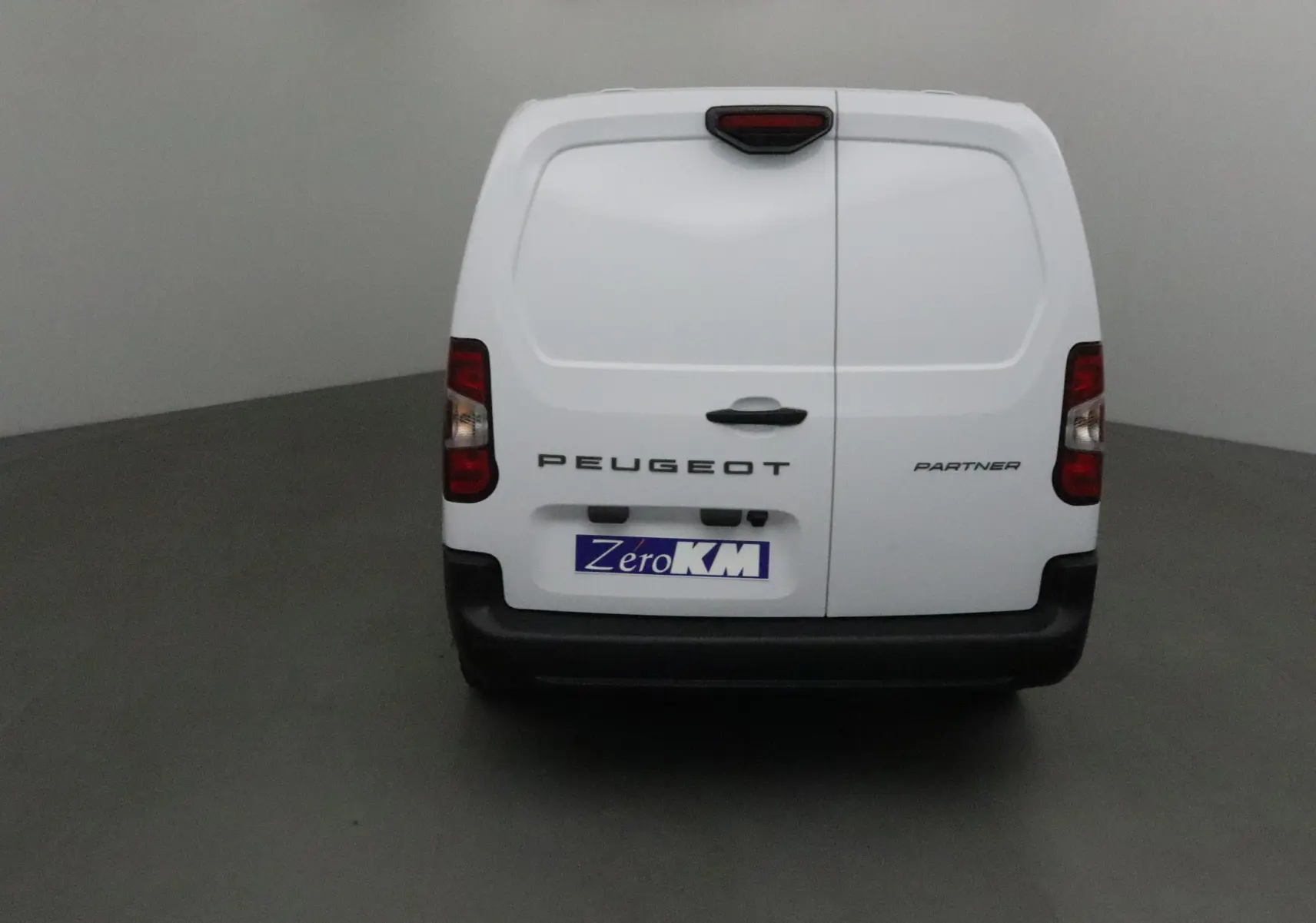 Vue arrière d'un utilitaire Peugeot Partner blanc avec portes battantes et logo visible sur fond neutre.