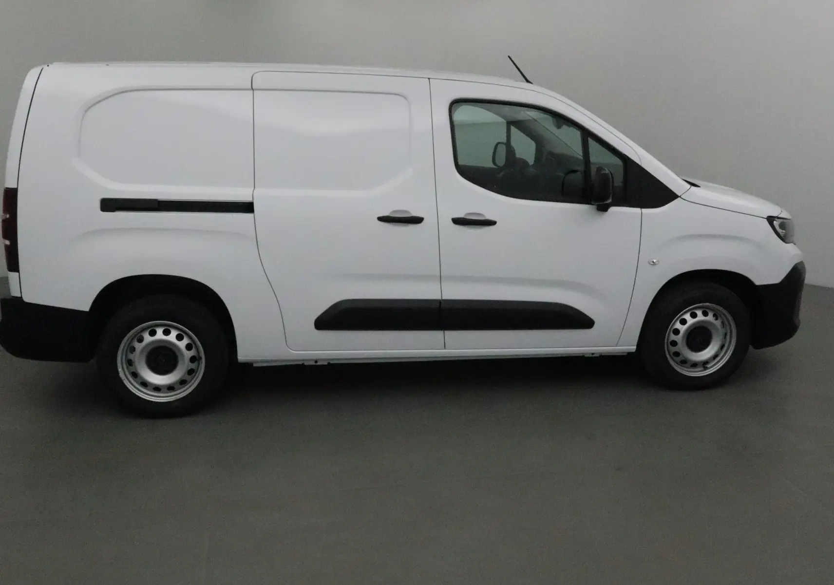 Profil côté droit du Peugeot Partner blanc 2025 avec portes coulissantes et jantes acier simples.