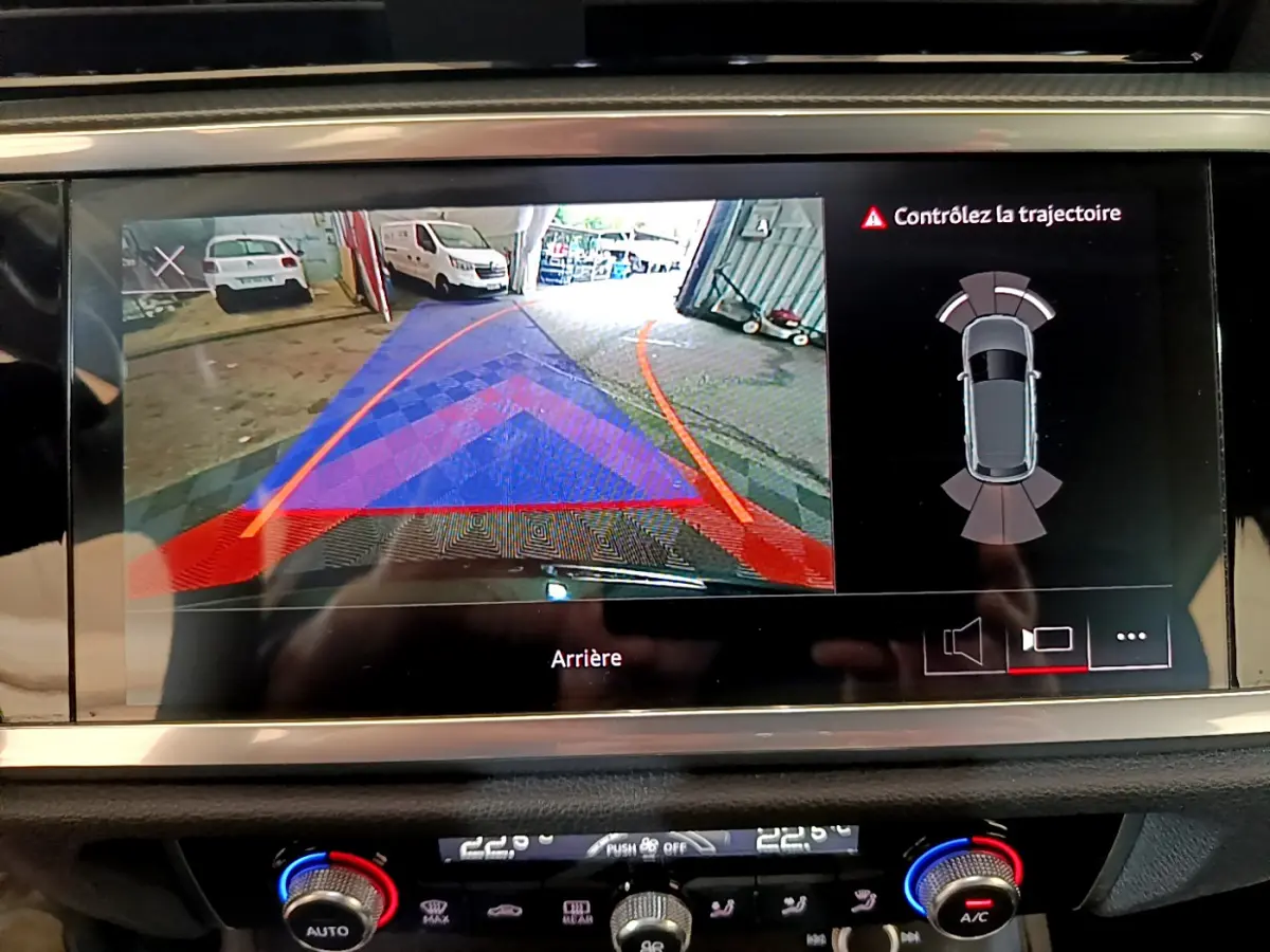 Écran tactile intérieur montrant la caméra de recul avec guidage et alertes sur un Audi Q3 noir de 2021.
