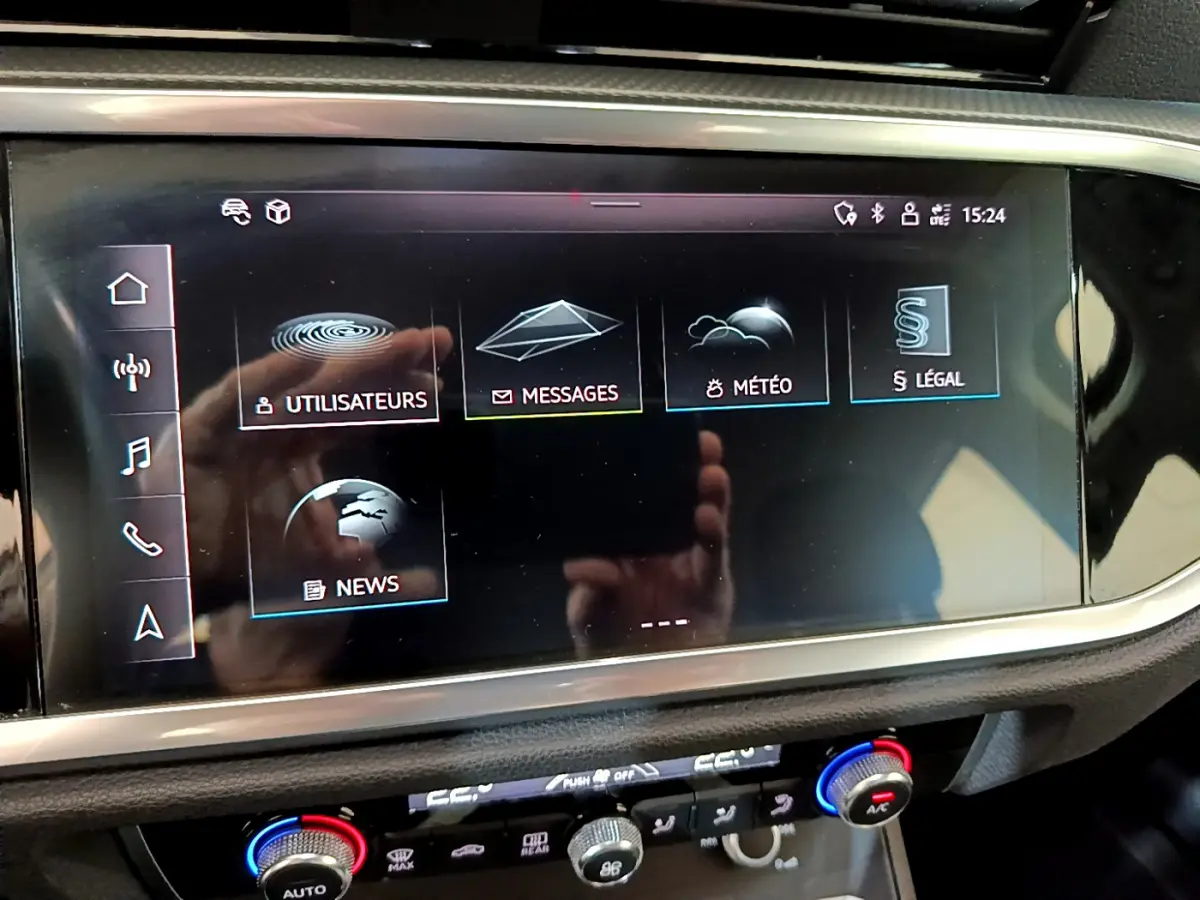 Écran tactile central de l'Audi Q3 35 TDI 2021 affichant le menu principal avec commandes climatisation en dessous.