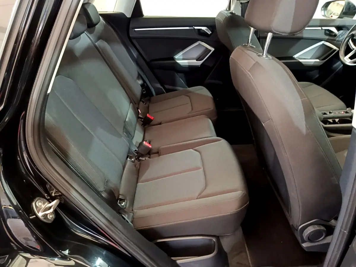 Vue intérieure côté gauche sur la banquette arrière noire de l’Audi Q3 35 TDI 2021 avec sièges tissu et appuie-têtes réglables.