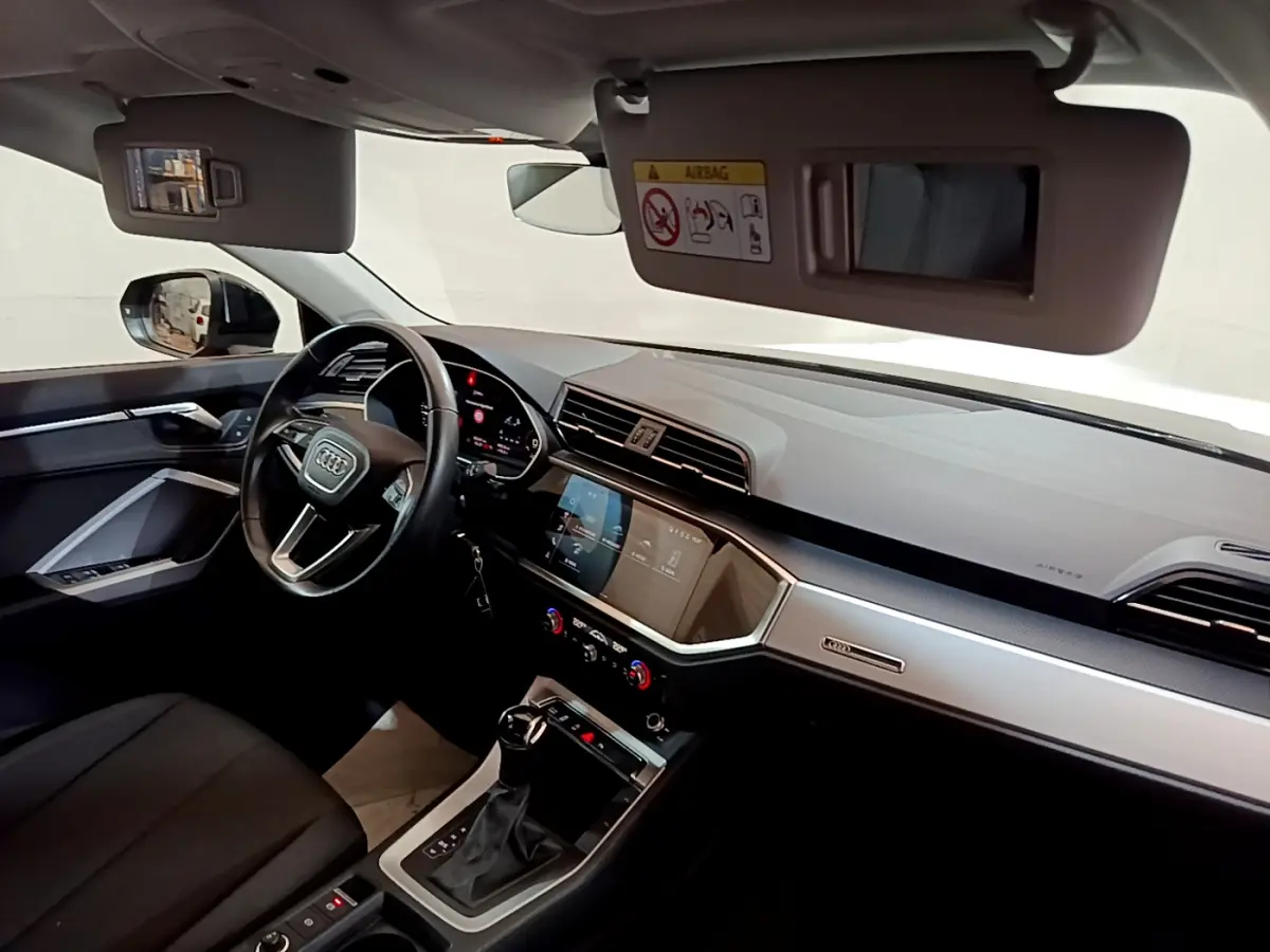 Intérieur Audi Q3 35 TDI 2021 vu côté conducteur, tableau de bord moderne avec écran tactile et volant cuir noir.