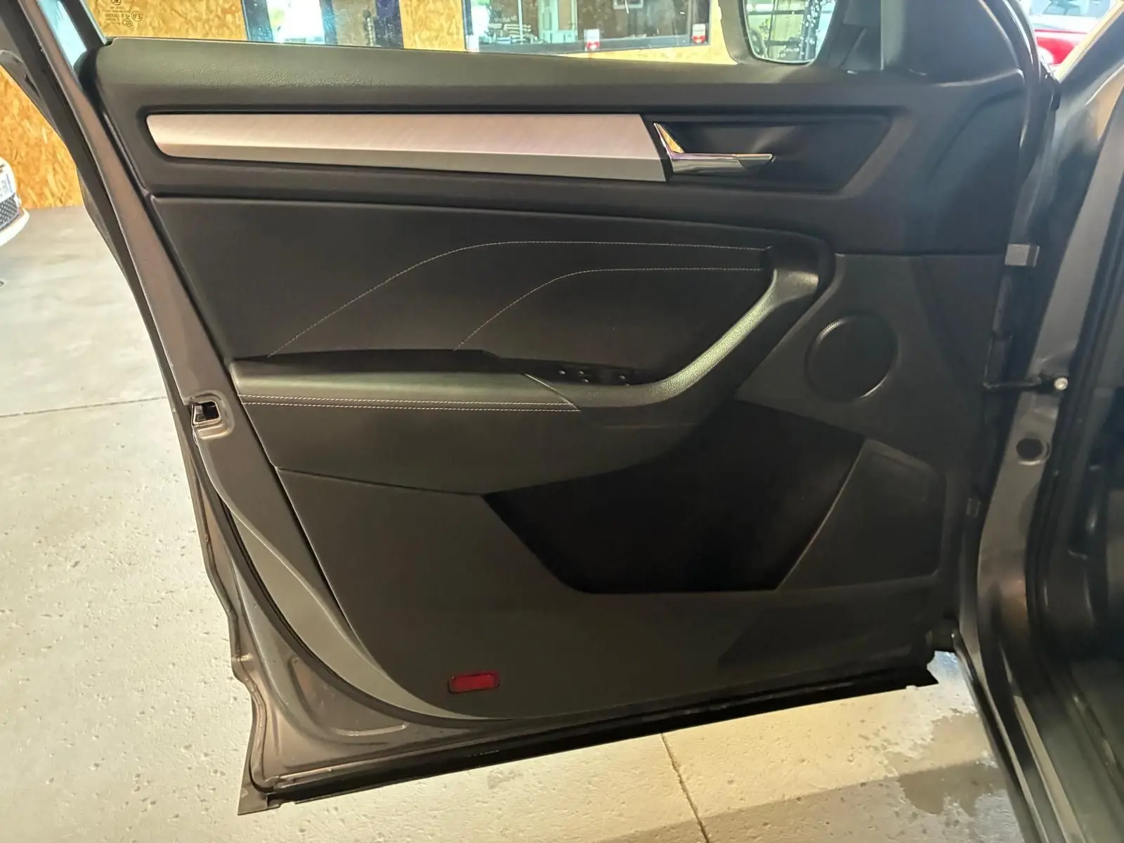Vue intérieure de la porte avant gauche gris foncé du Skoda Kodiaq 2023 avec insert décoratif aluminium brossé.
