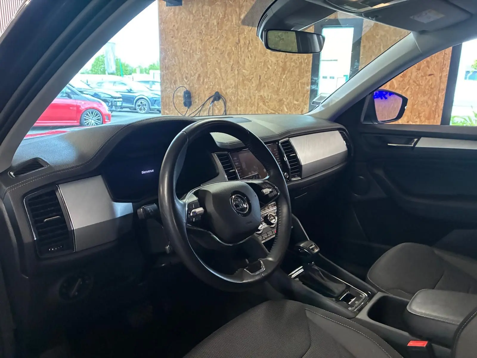 Vue intérieure côté conducteur du Skoda Kodiaq gris 2023, avec tableau de bord moderne et volant cuir noir.