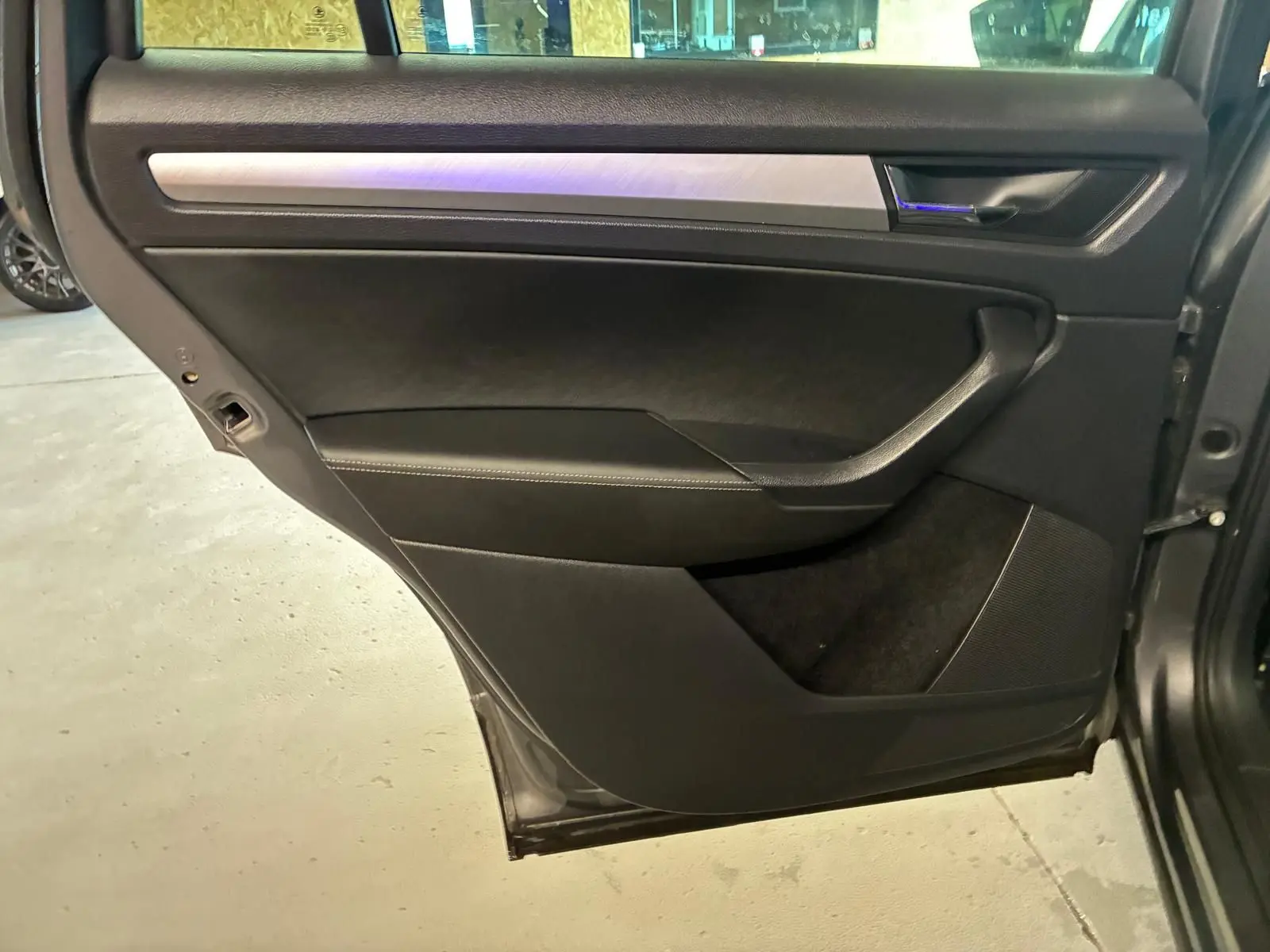Porte arrière droite ouverte du Skoda Kodiaq gris 2023, intérieur noir avec insert aluminium brossé.