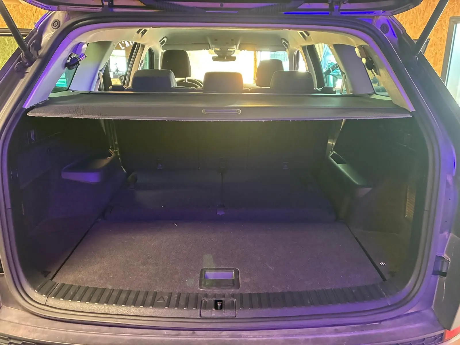 Vue arrière du coffre ouvert d'un SKODA KODIAQ gris 7 places, avec cache-bagages et sièges arrière visibles.