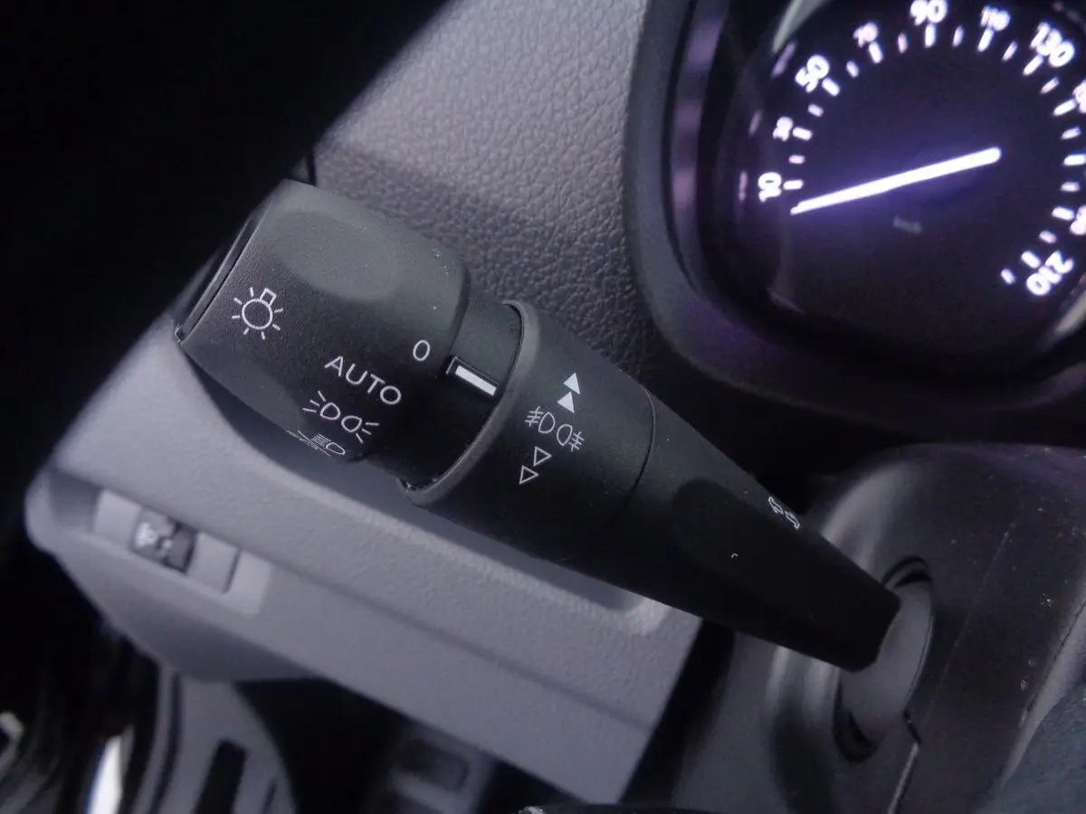 Gros plan sur la commande des phares du Peugeot Expert Fourgon noir métal, avec tableau de bord partiellement visible.